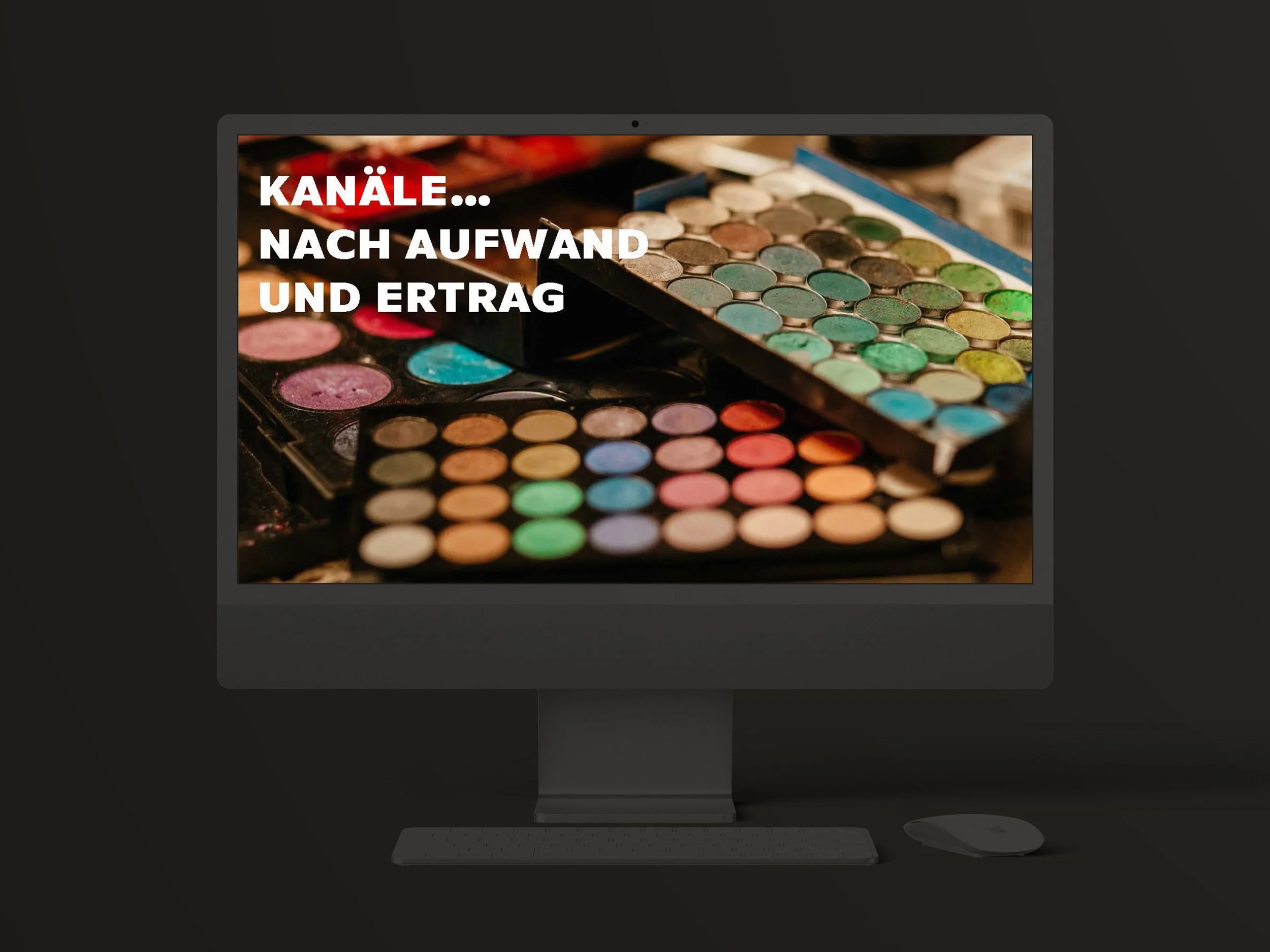 Ein Computerbildschirm zeigt die Titelfolie einer Präsentation, vor einem Hintergrund mit bunten Make-up-Paletten.