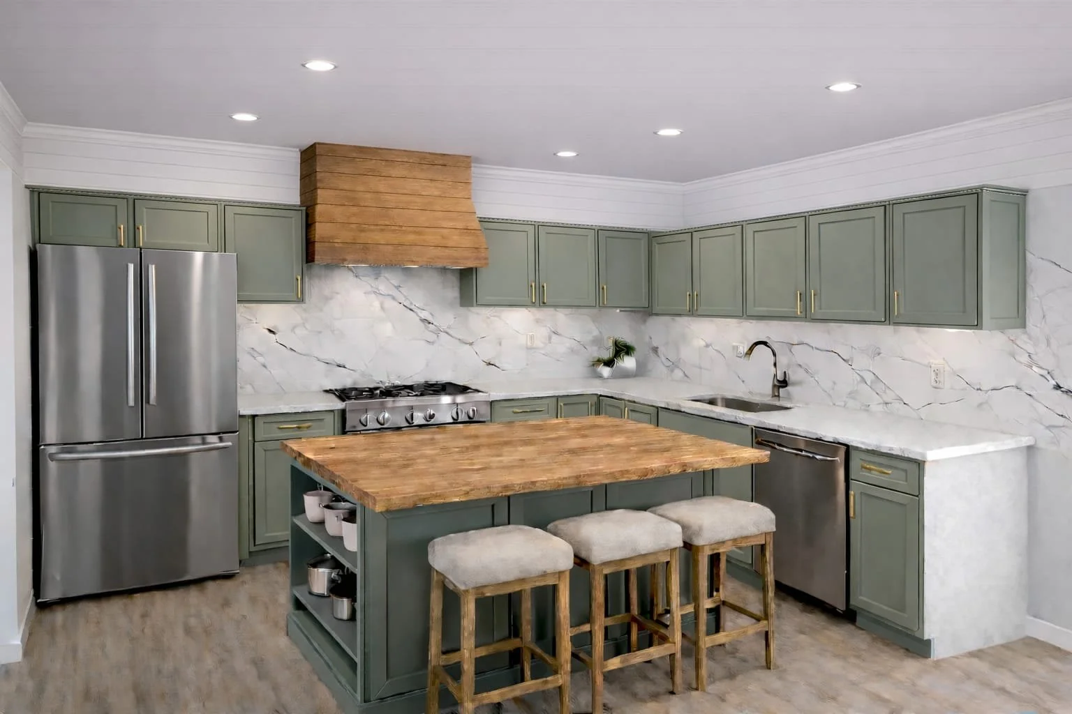 Modern kitchen with green cabinets, marble backsplash, wooden island, stainless steel refrigerator and sink, and ceiling lights.