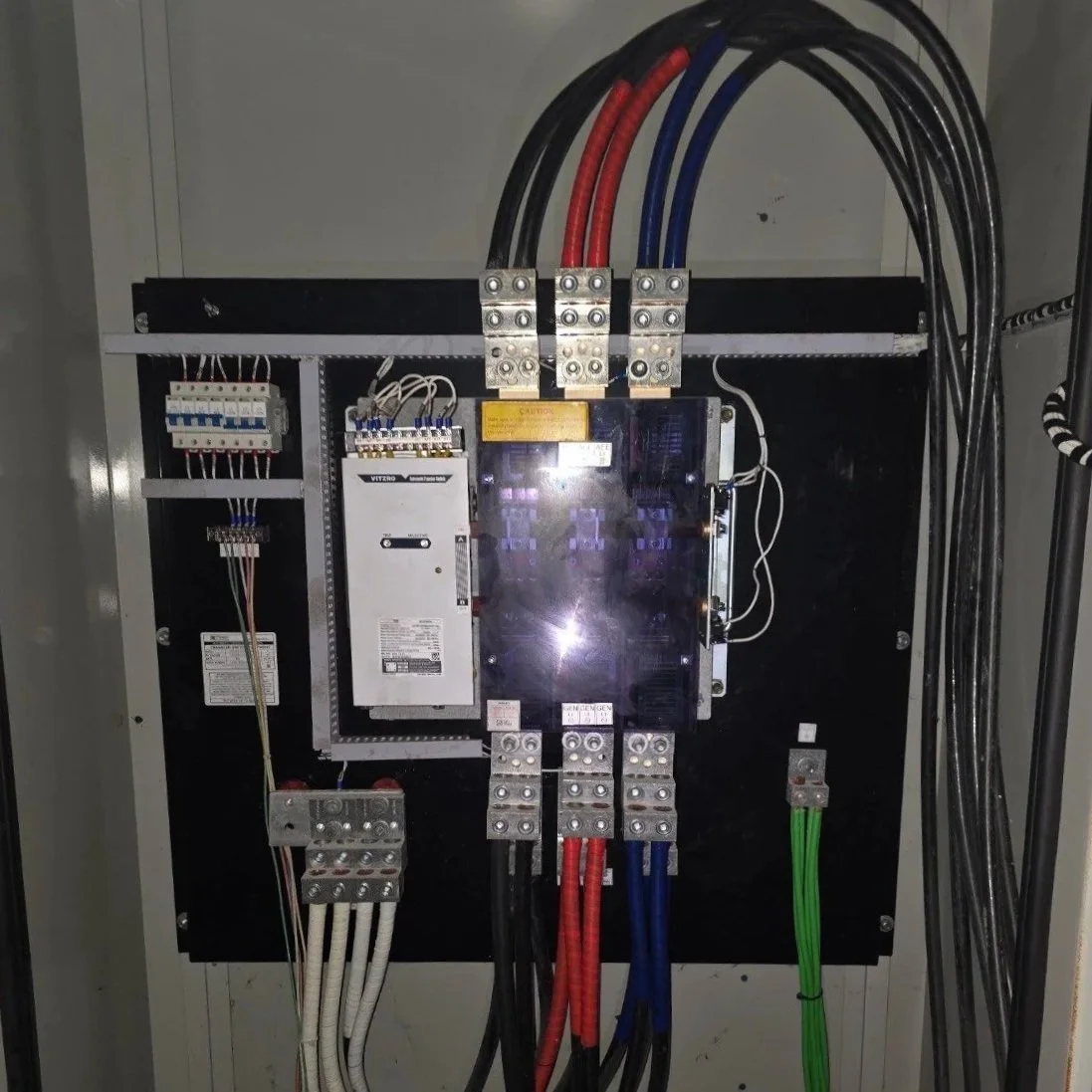 Electrical control panel with various colored wires and circuit breakers.
