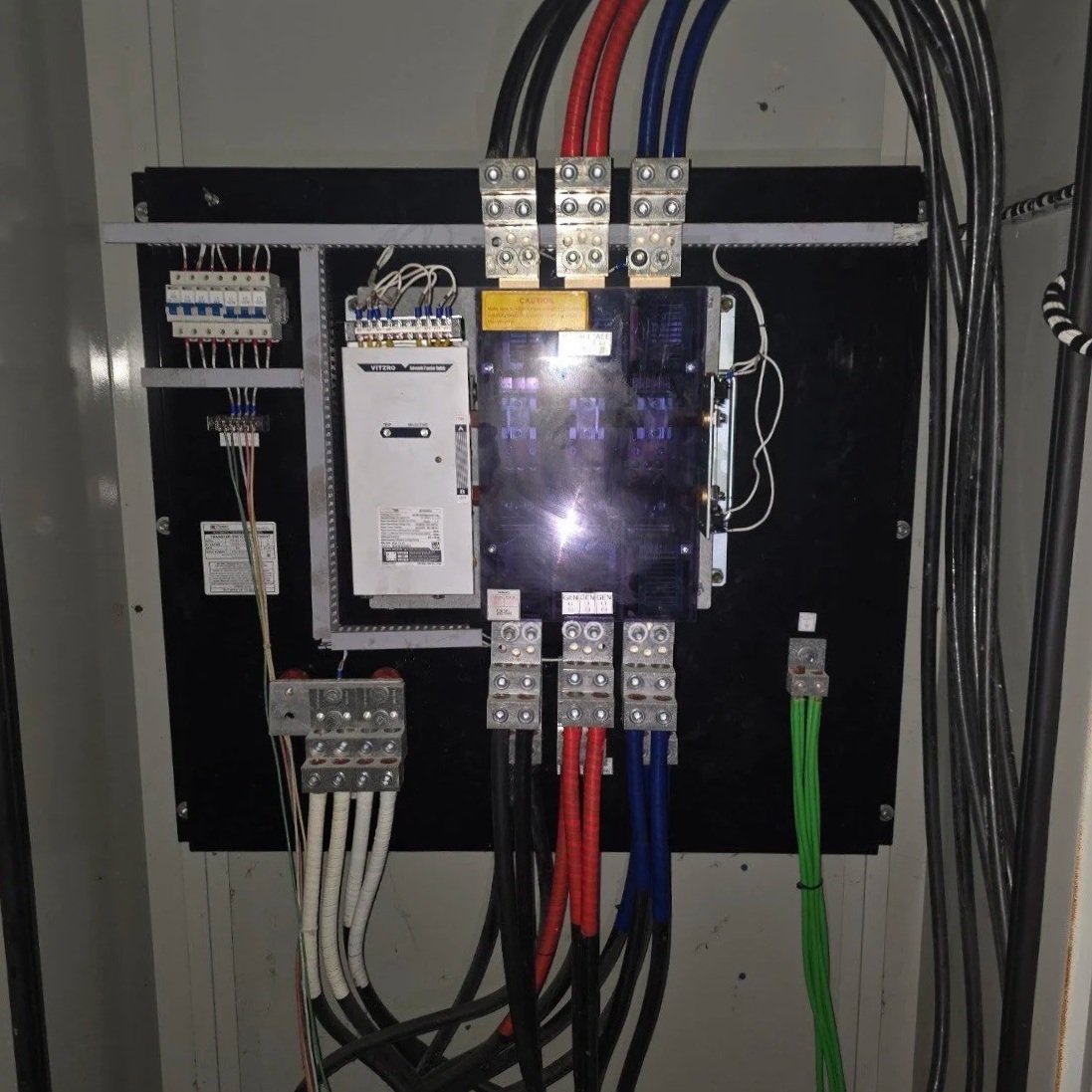 Electrical control panel with various wires, circuit breakers, and components inside a metal enclosure.