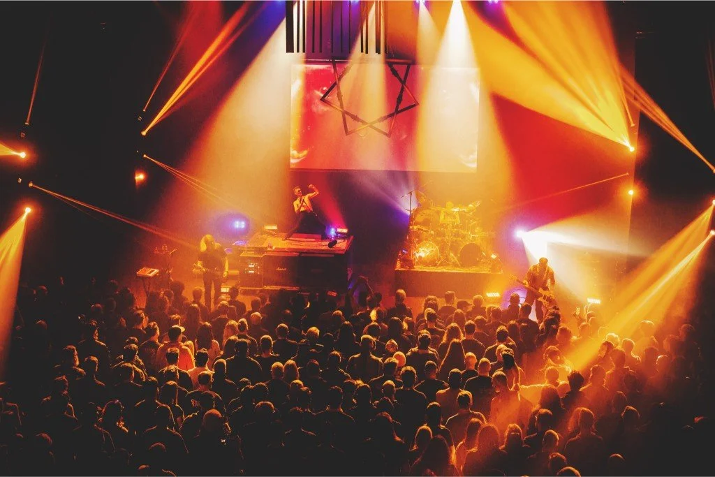 Concert stage with performers, colorful lighting, and an audience