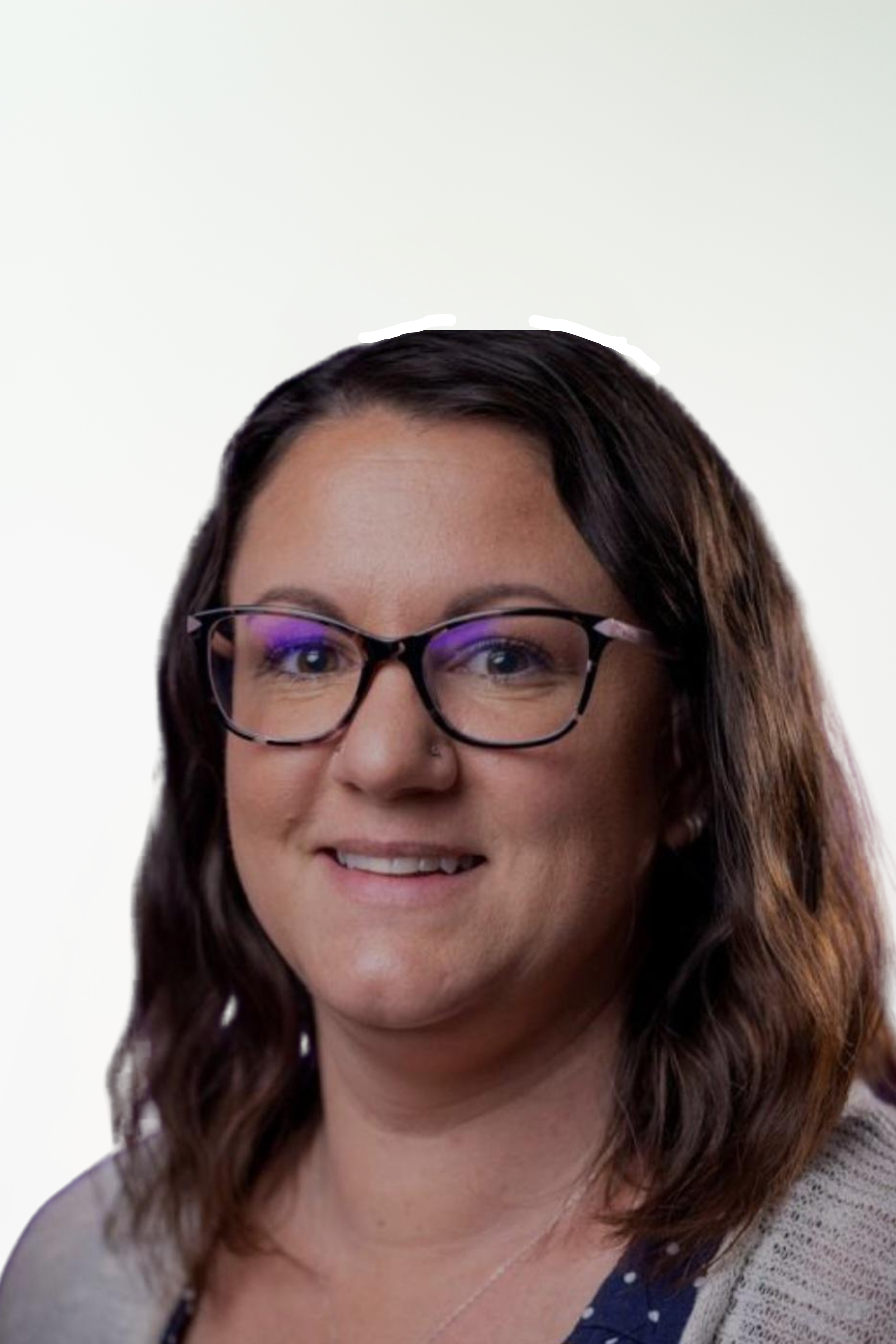 A woman with glasses and brown hair smiling, wearing a navy blue top with white polka dots and a gray cardigan.