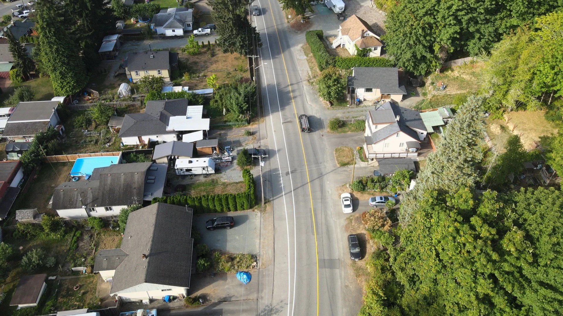 Aerial view of a residential neighborhood with houses, trees, and cars parked along the streets and driveways.