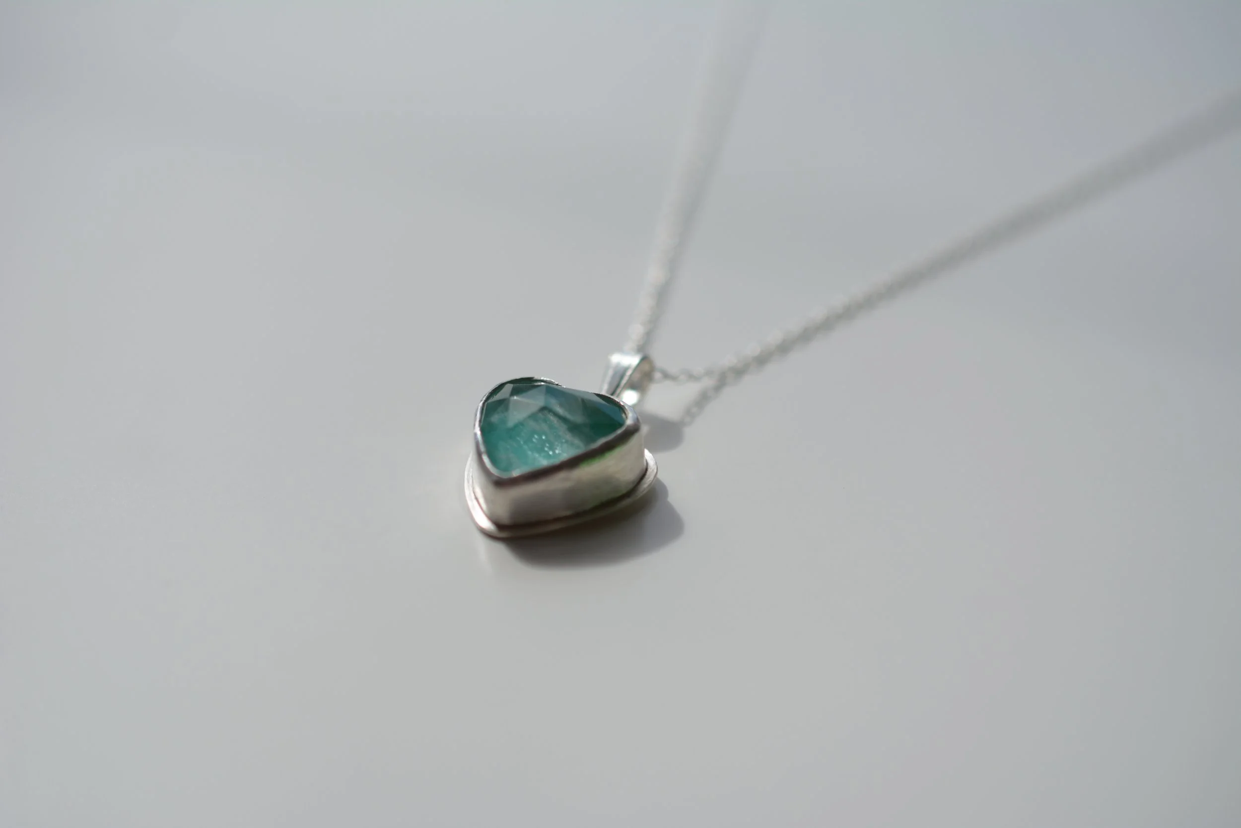 Heart-shaped amazonite and quartz doublet pendant in a handmade recycled silver bezel, hanging from a silver chain on a pale background