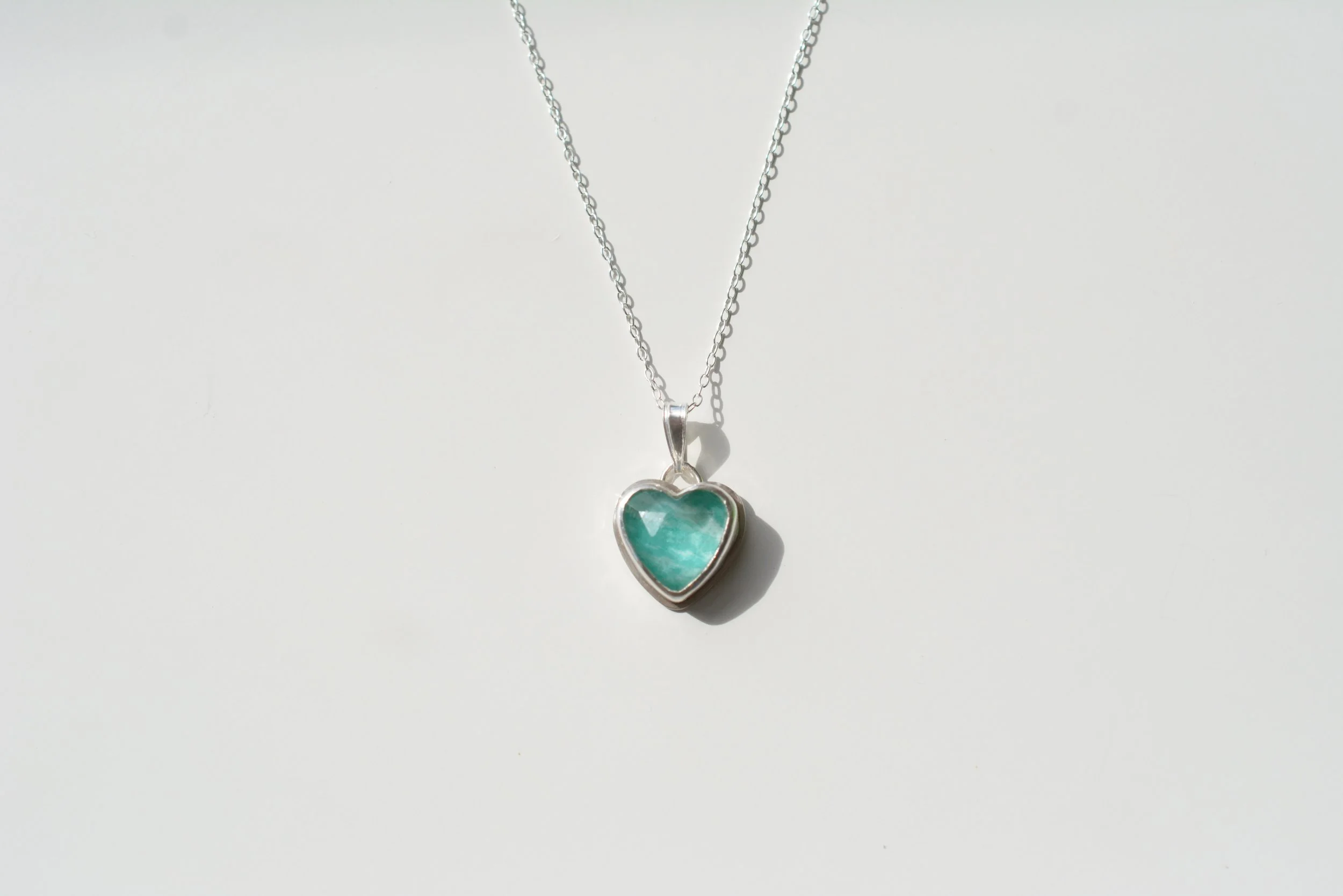 Heart-shaped amazonite and quartz doublet pendant in a handmade recycled silver bezel, hanging from a silver chain on a pale background
