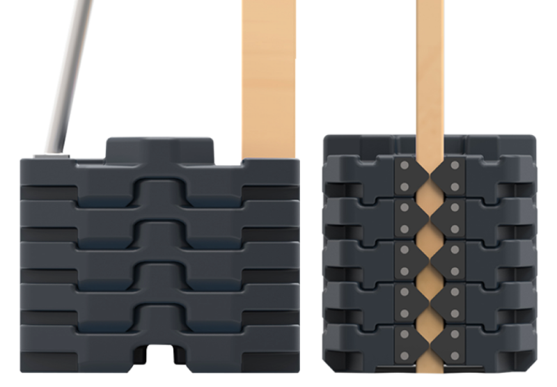 Stack of black plastic parts on a workbench with a wooden board and a metallic pipe.