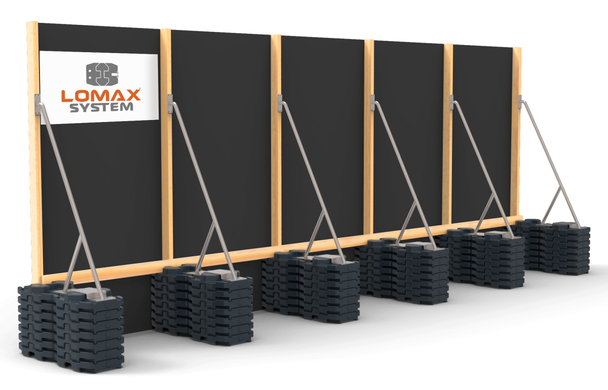 A wall with black panels and wooden framing, with multiple black weight blocks stacked at the base and metal support bars leaning against the wall.