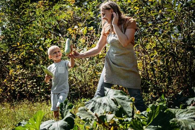 Mother in the garden with her son, holding a vegetable