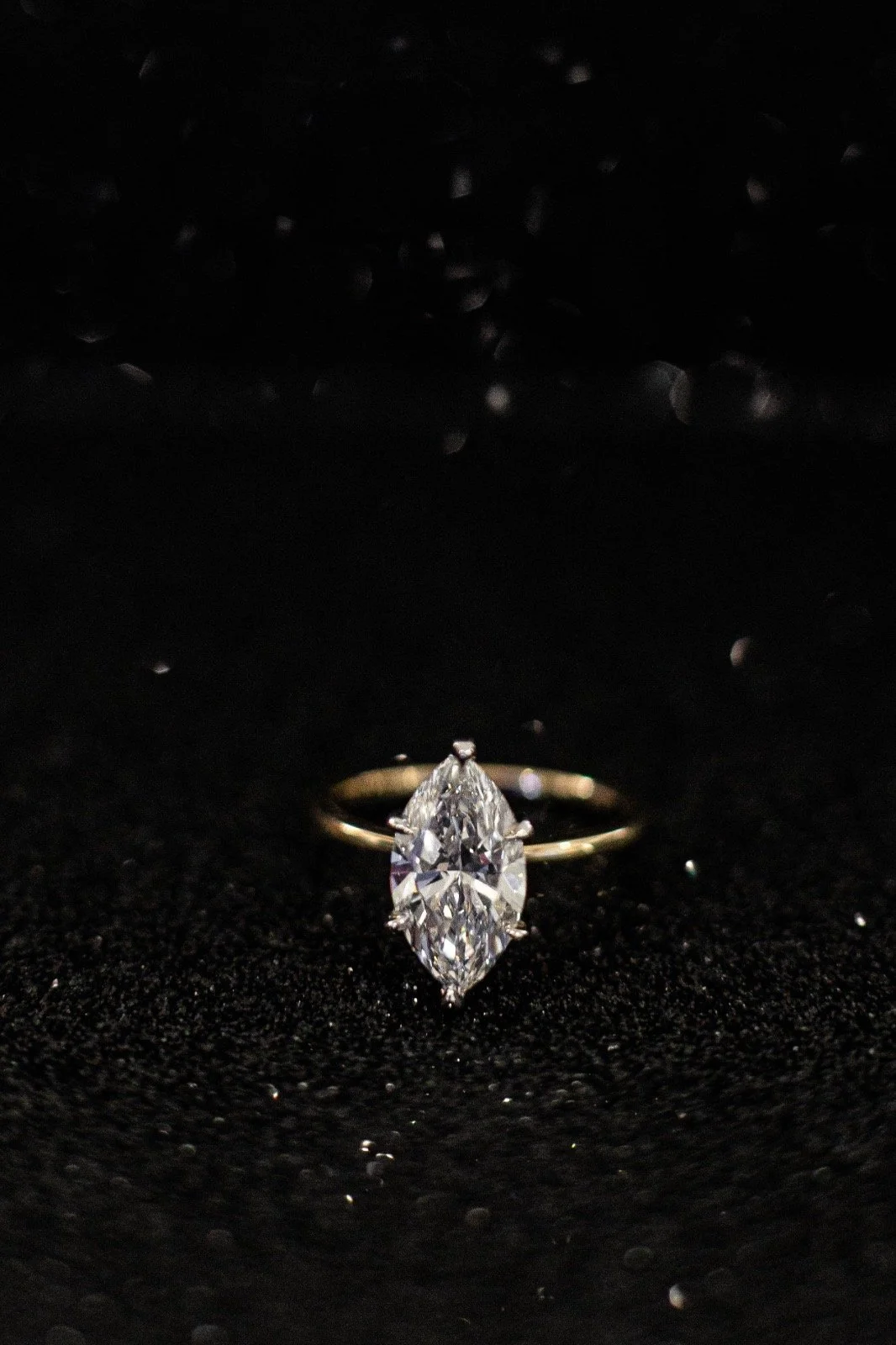 A diamond ring with a marquise-cut diamond on a black background.
