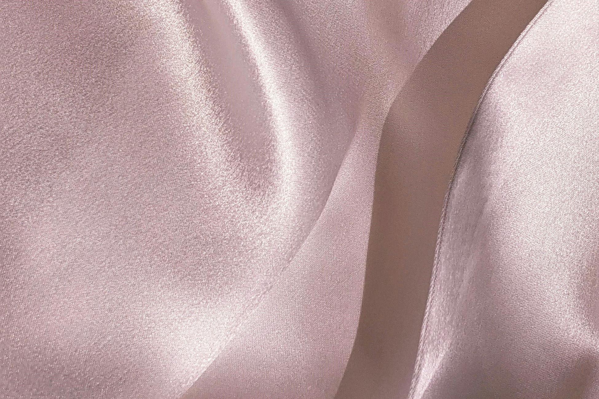 Close-up of pink satin fabric with smooth, shiny, and flowing texture.