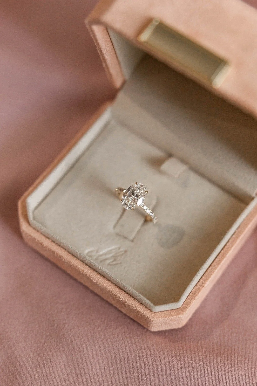 A diamond engagement ring in a pink jewelry box with a soft interior