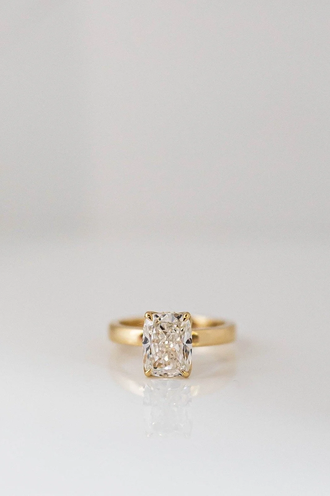 A gold ring with a large rectangular cut diamond solitaire setting.