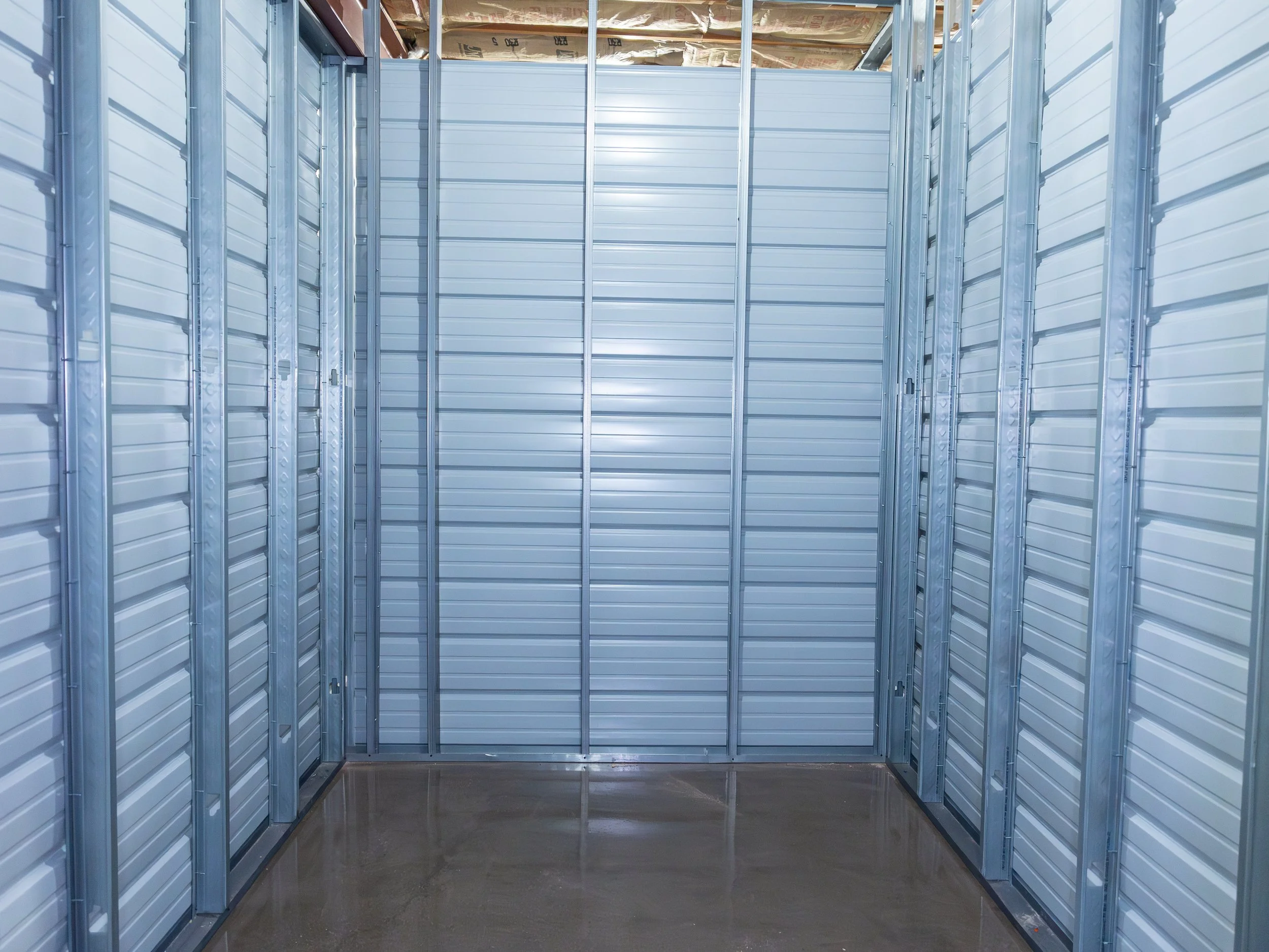 Empty storage unit with metal walls, framework, and a high ceiling.