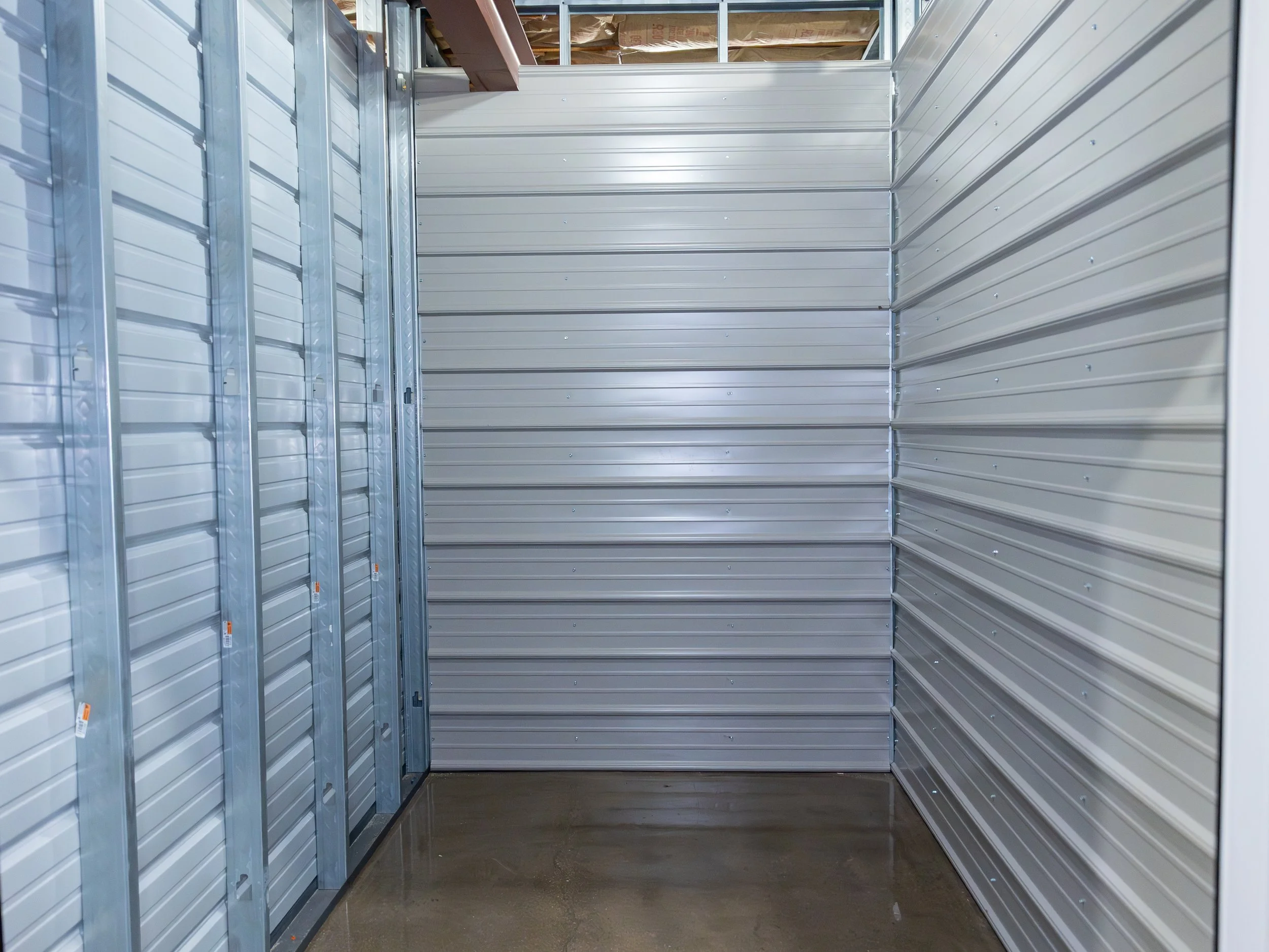 Empty storage unit with metal walls and a concrete floor.
