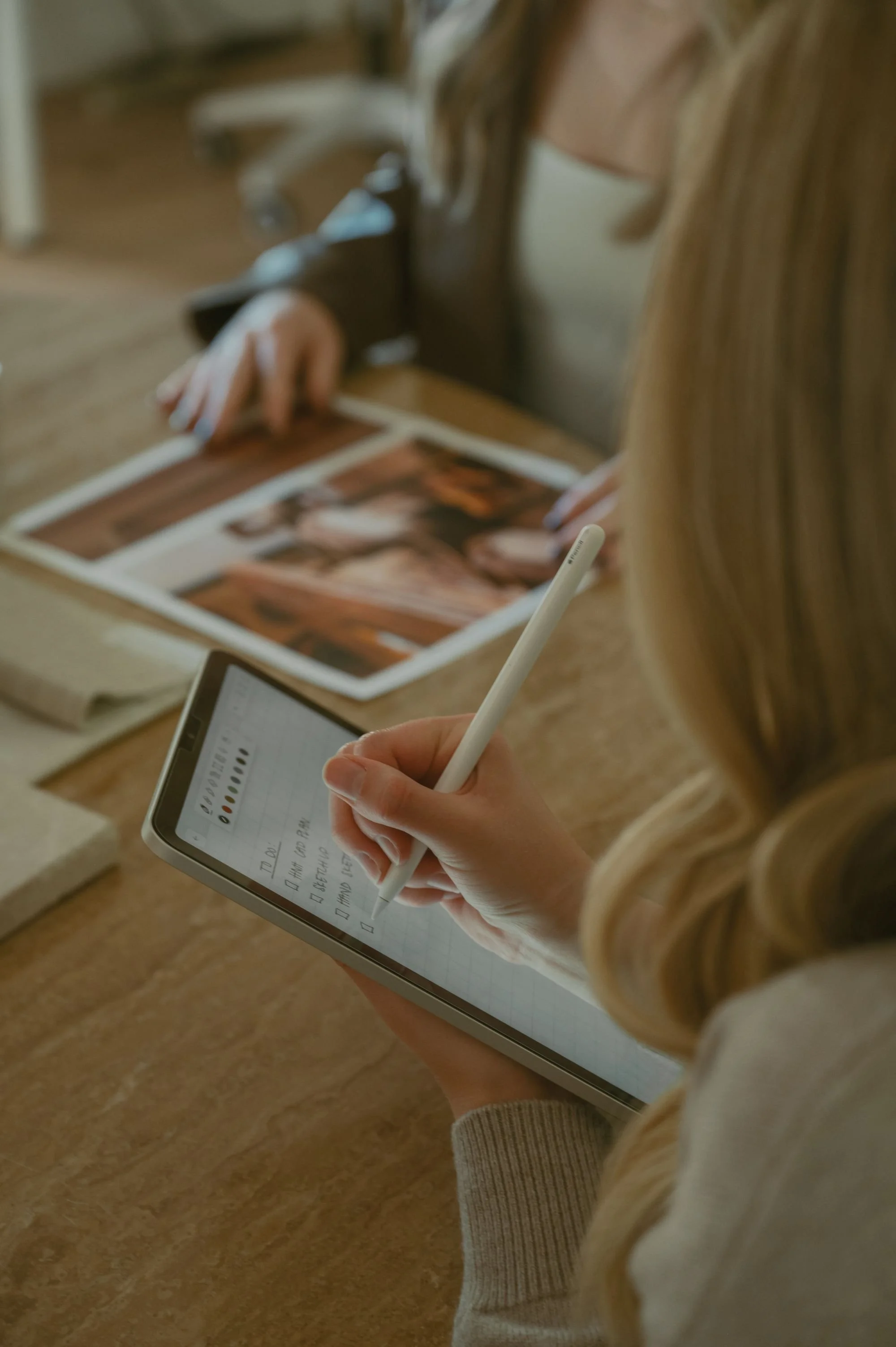Interior designer reviewing printed photo layouts and design inspiration on a table.