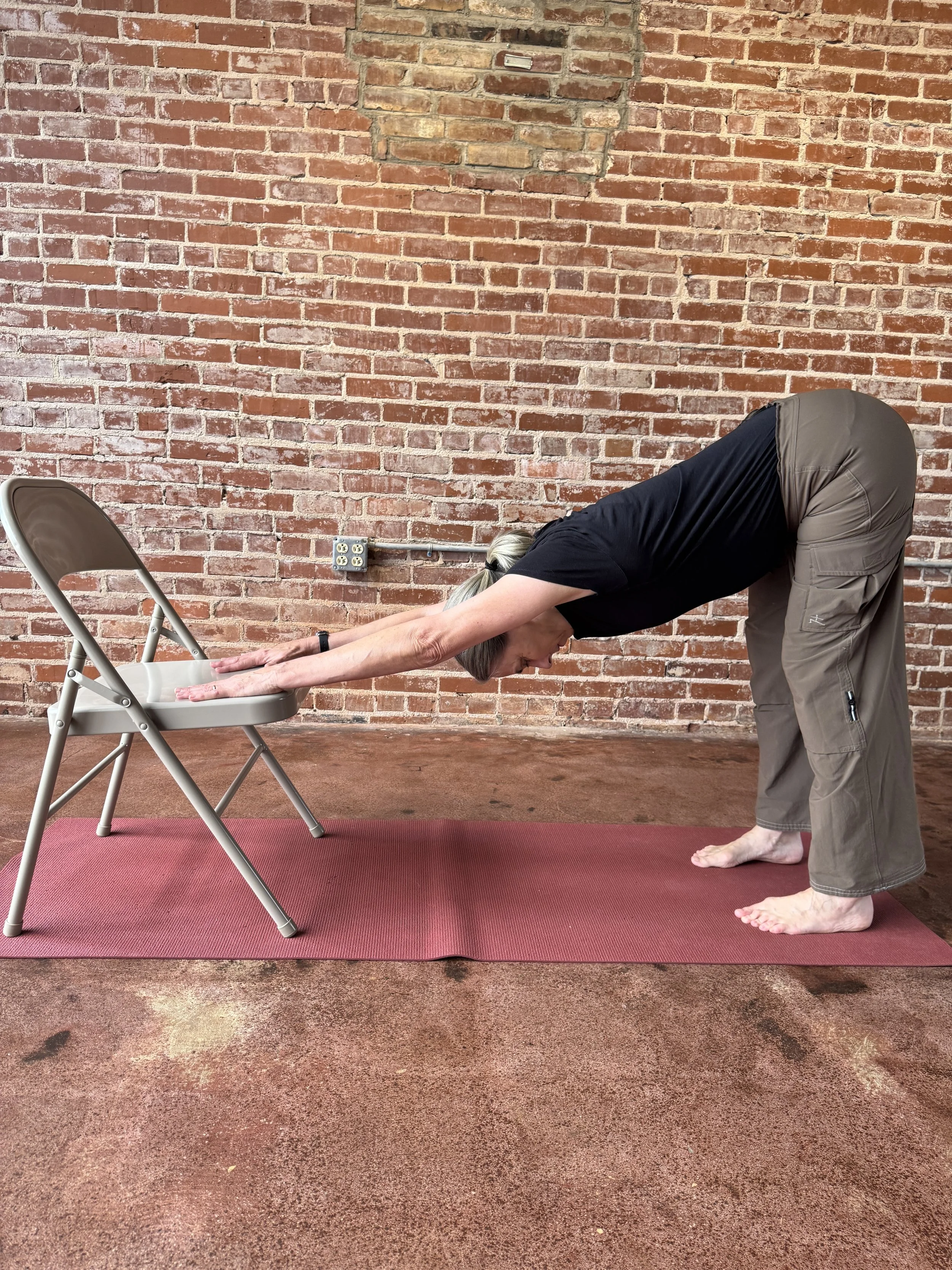 Woman in downward facing dog pose using a chair