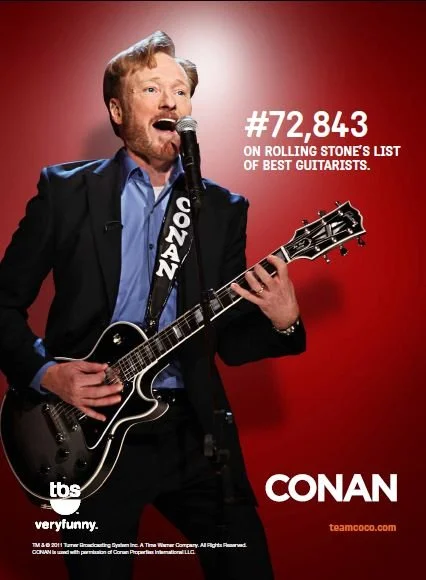 Conan O'Brien performing with a guitar, singing into a microphone against a red background, with text indicating he's number 72,843 on Rolling Stone's list of best guitarists.