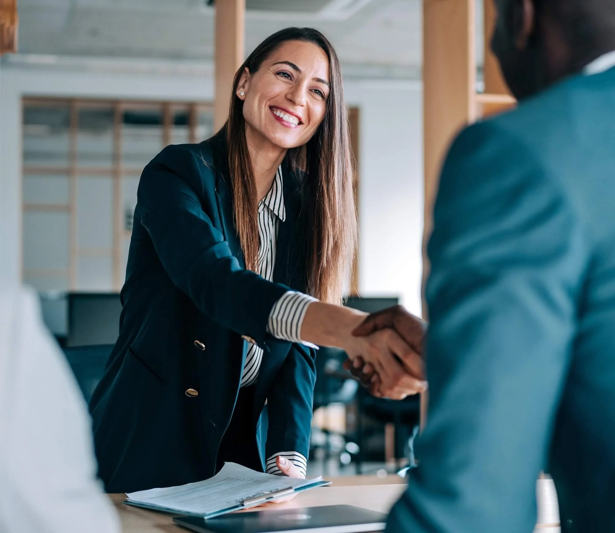 Businesswoman shaking hands with client while closing a deal.