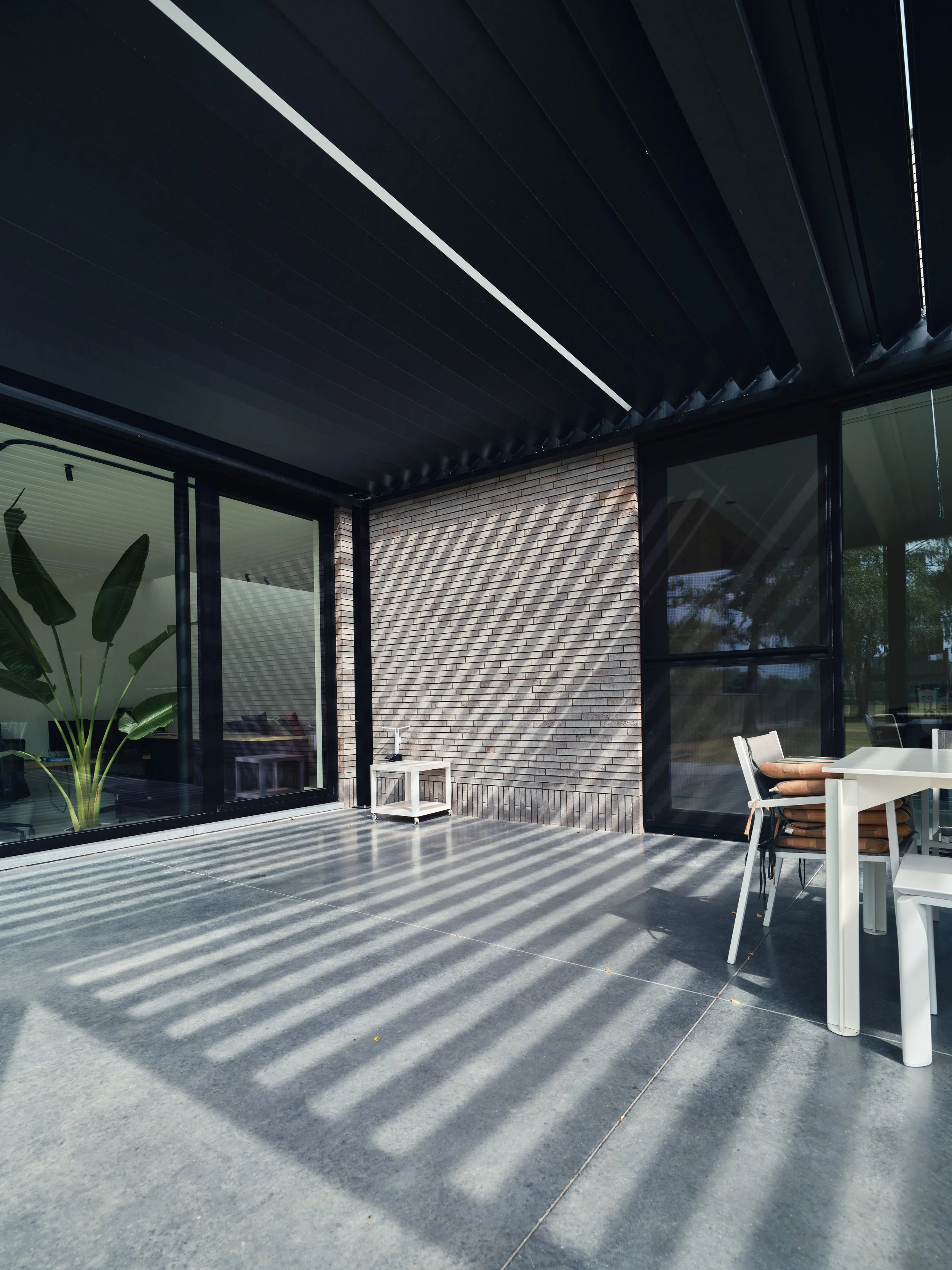 zwarte Renson Algarve lamellendak met verlichting aangebouwd tegen moderne woning in Puurs-Sint-Amands, Antwerpen