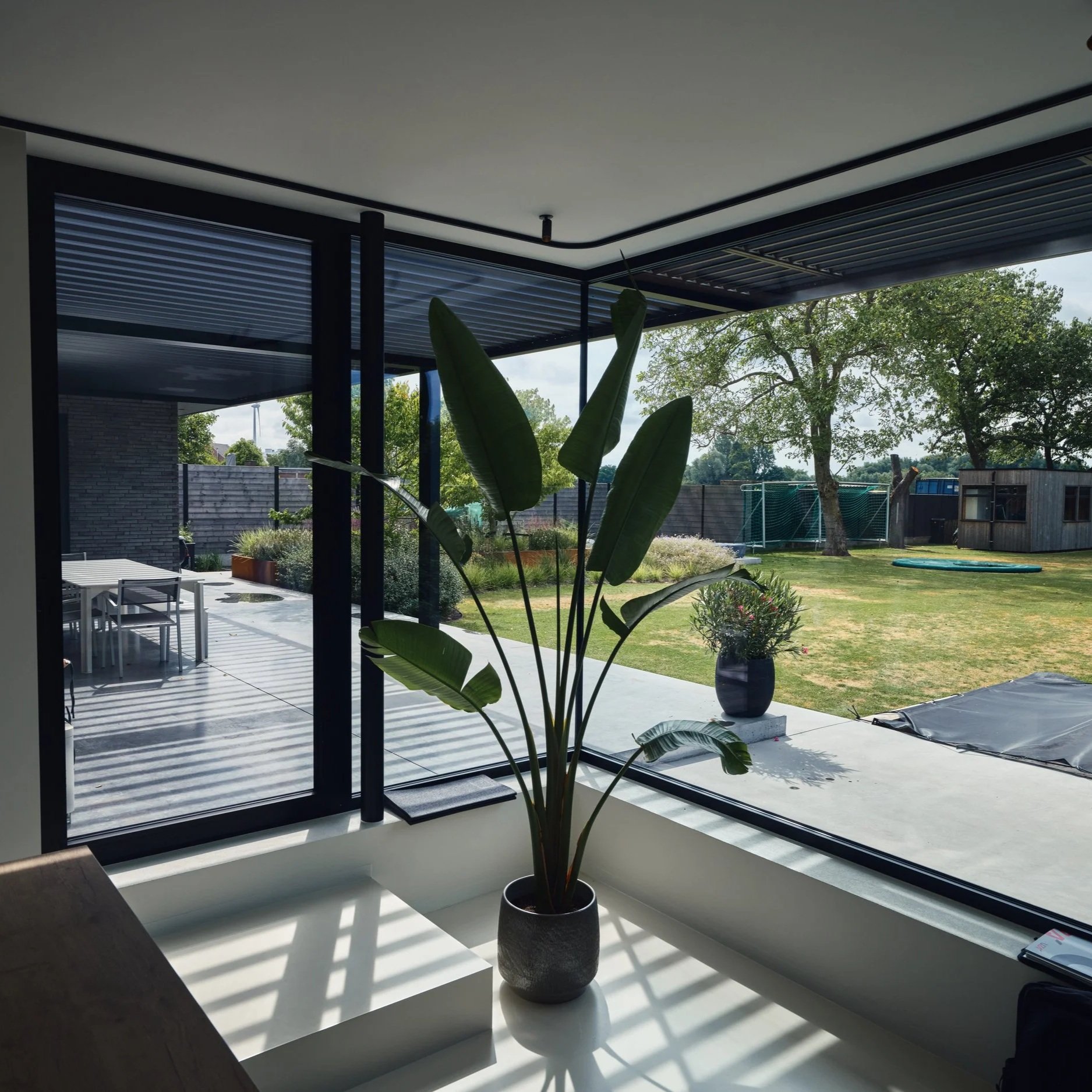 Glas op glas raam in Reynaers aluminium profielen type Masterline 8 uitgevoerd in zwarte kleur bij een moderne woning