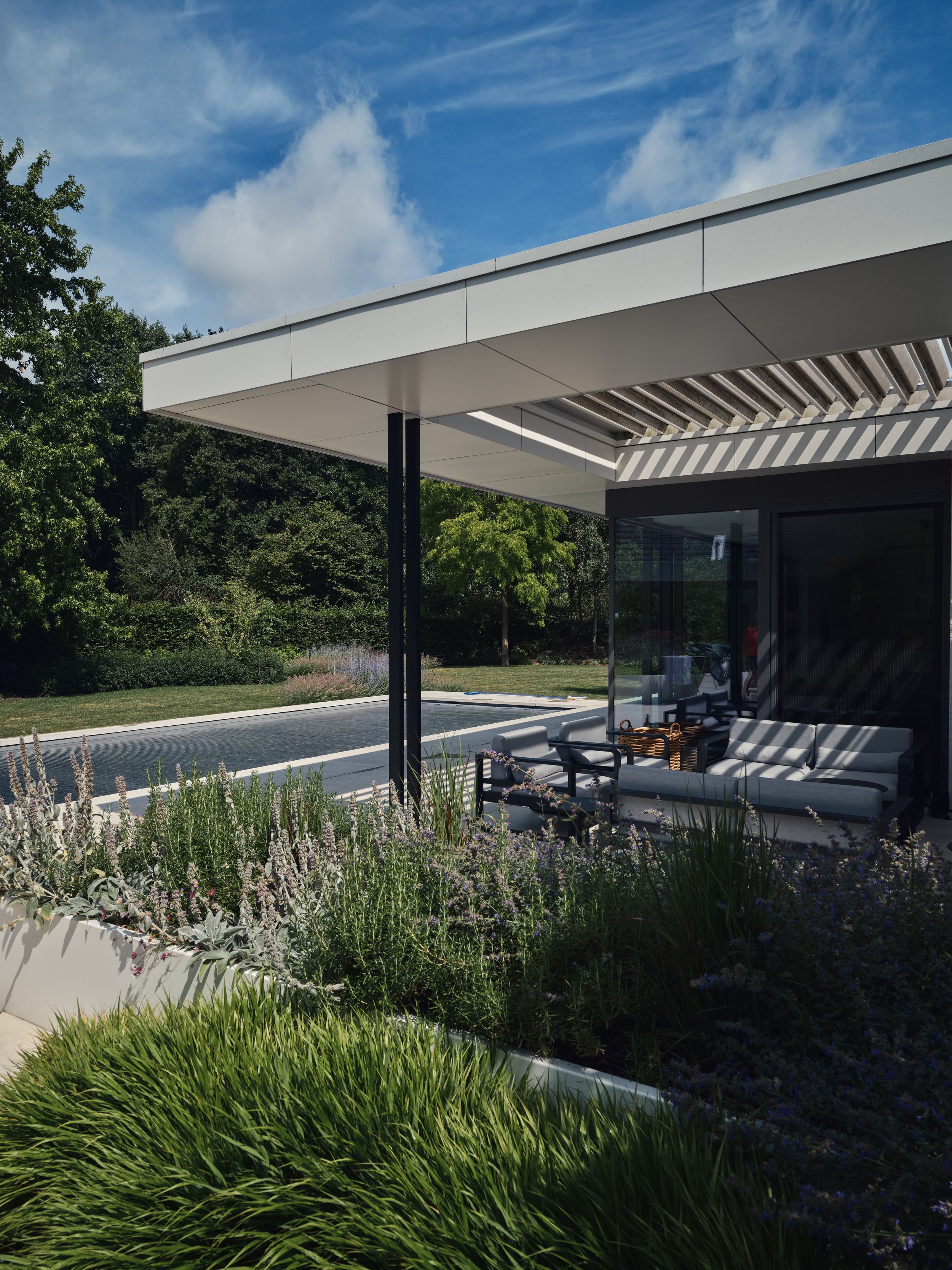 Modern Poolhouse, voorzien van een Renson lamellendak, type aero in witte kleur in Puurs-Sint-Amands, Antwerpen dat geplaatst is door Leroy-alu