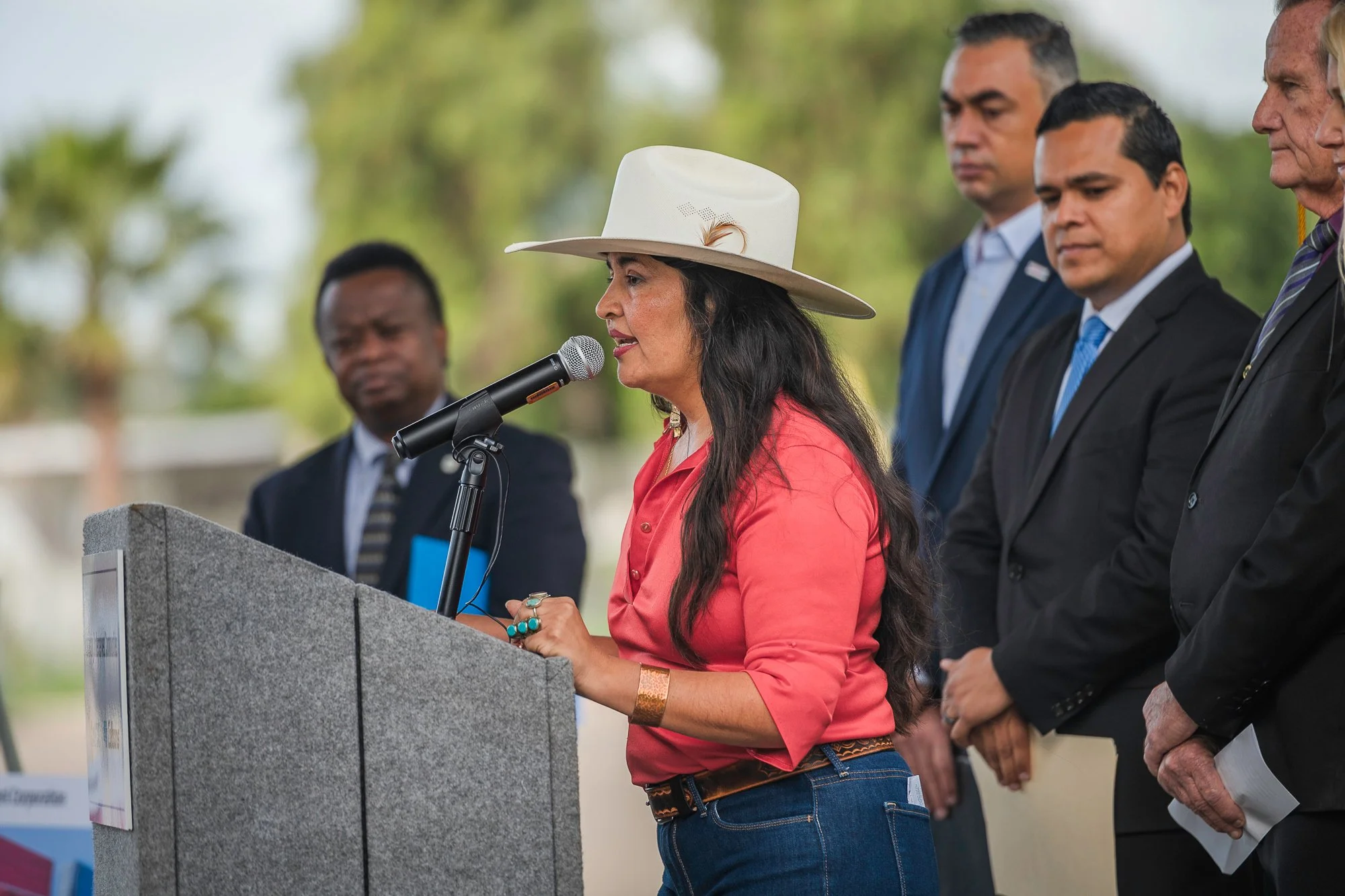 Mundo Gardens executive Janice Reynoso speaking at a podium to celebrate the State's $25 million commitment.