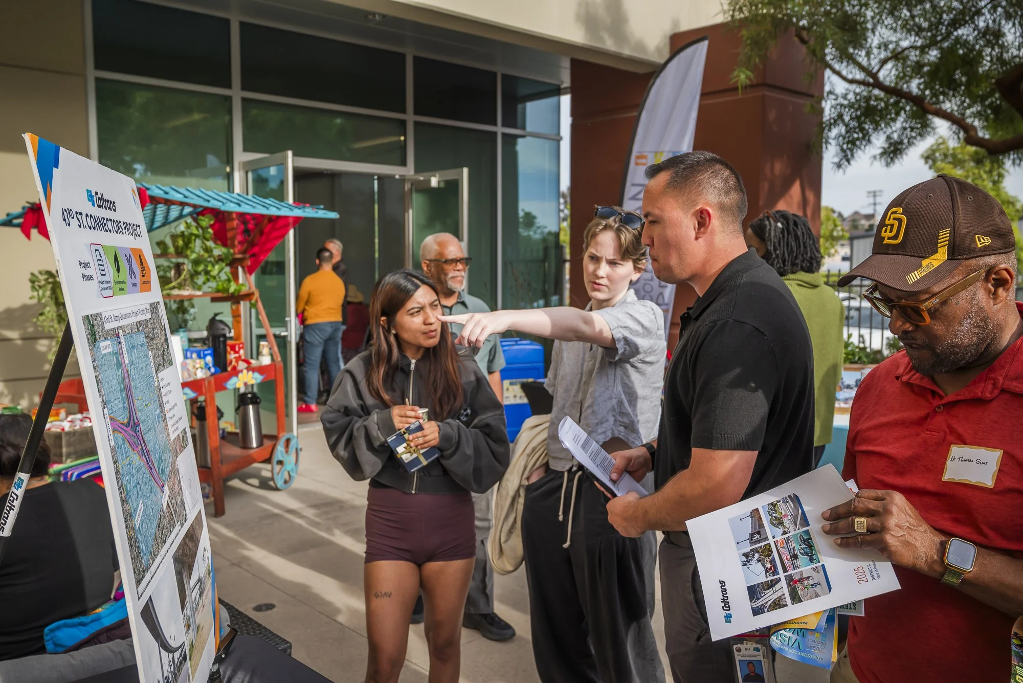 People attending an outdoor informational event, looking at posters and engaging in discussion.