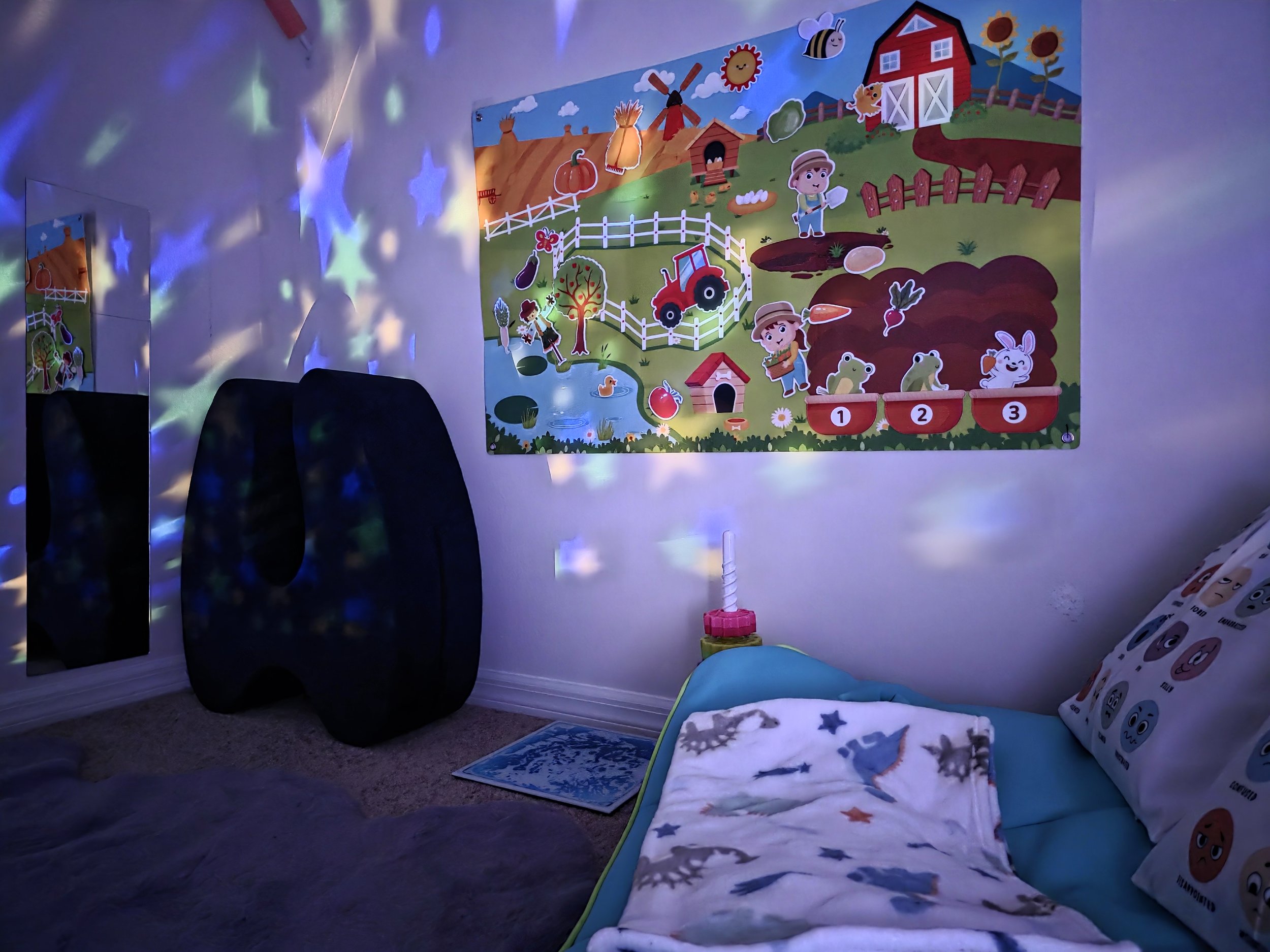 A children's room with a colorful farm-themed poster on the wall, a bed with animal print pillows and a blanket, a mirror reflecting the room, and star-shaped lights creating a starry effect on the walls.