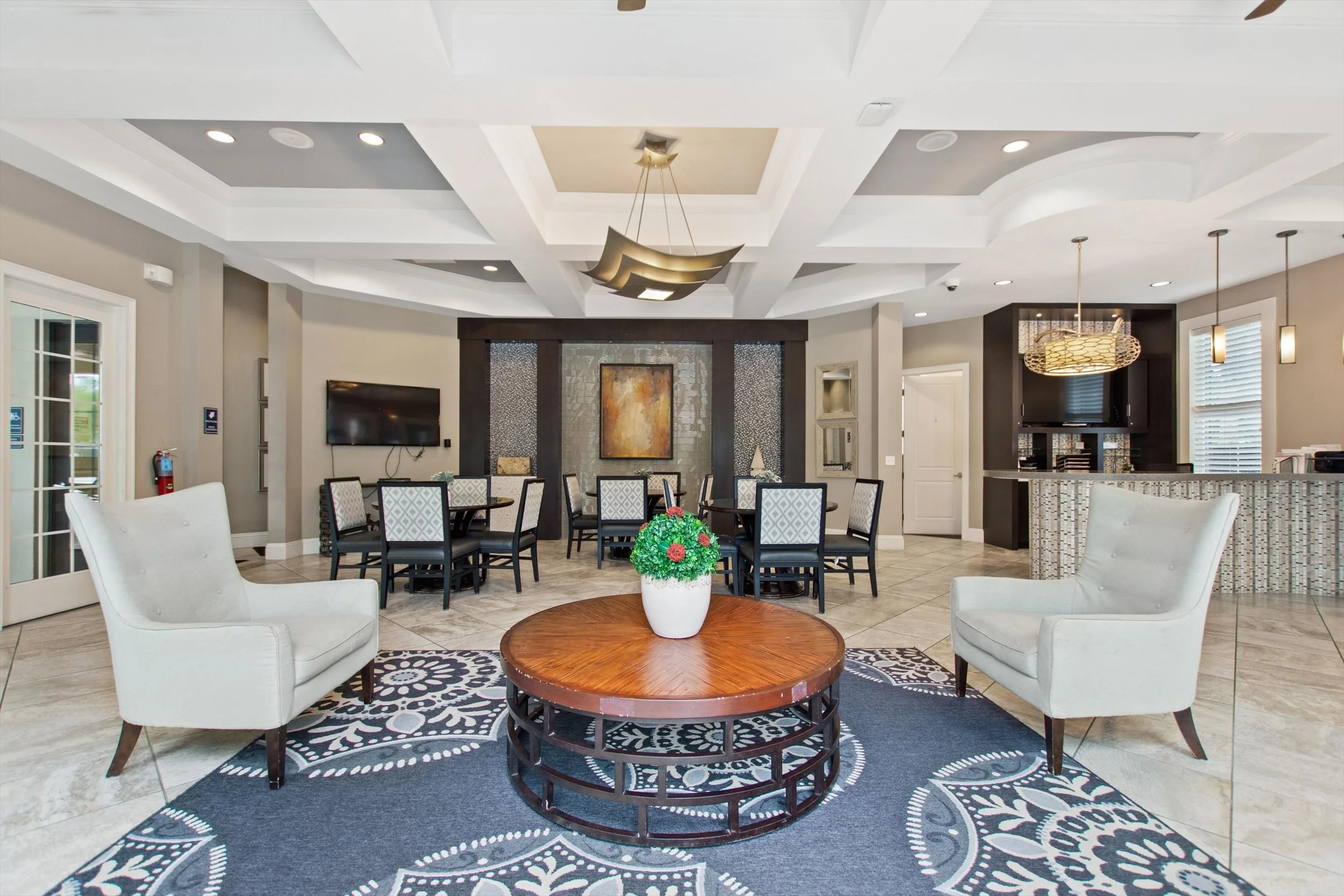 Luxurious hotel lobby with seating area, a coffee table with a potted plant, dining tables, and a bar, featuring modern decor and lighting.