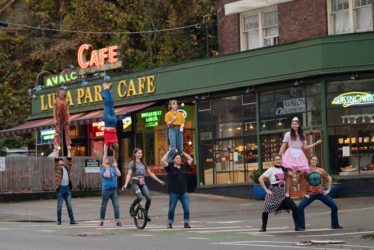 Performers show off acrobatics in front of a café representing the show's fictional cafe, The Sacred Store.