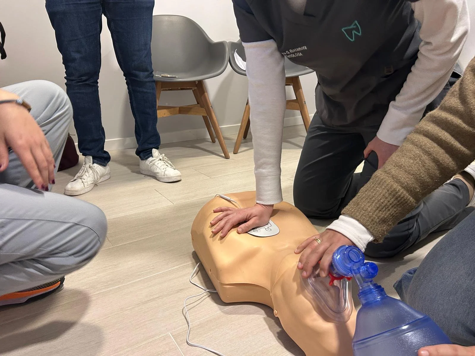 Personas realizando un entrenamiento de reanimación en una máscara de simulación de tórax en un espacio interior.