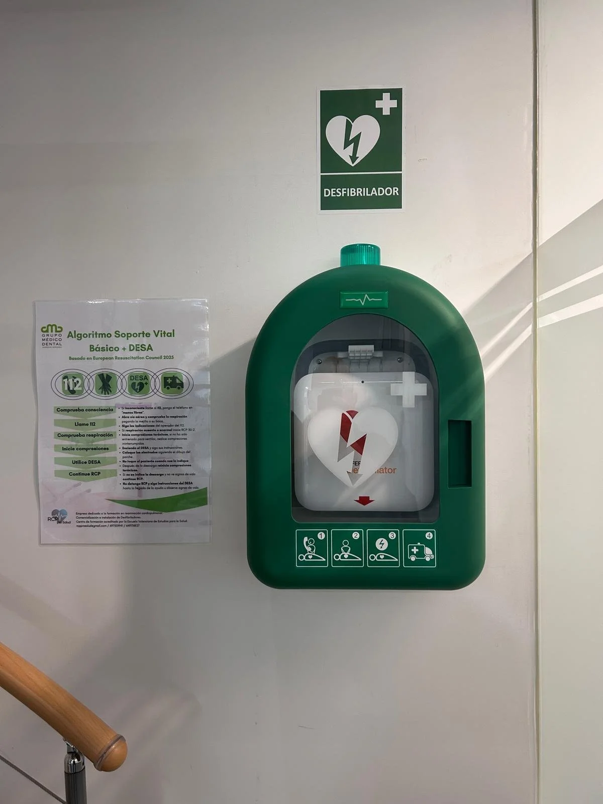 Desfibrilador en la pared con señal de ayuda de resucitación cardiopulmonar y instrucciones para su uso.