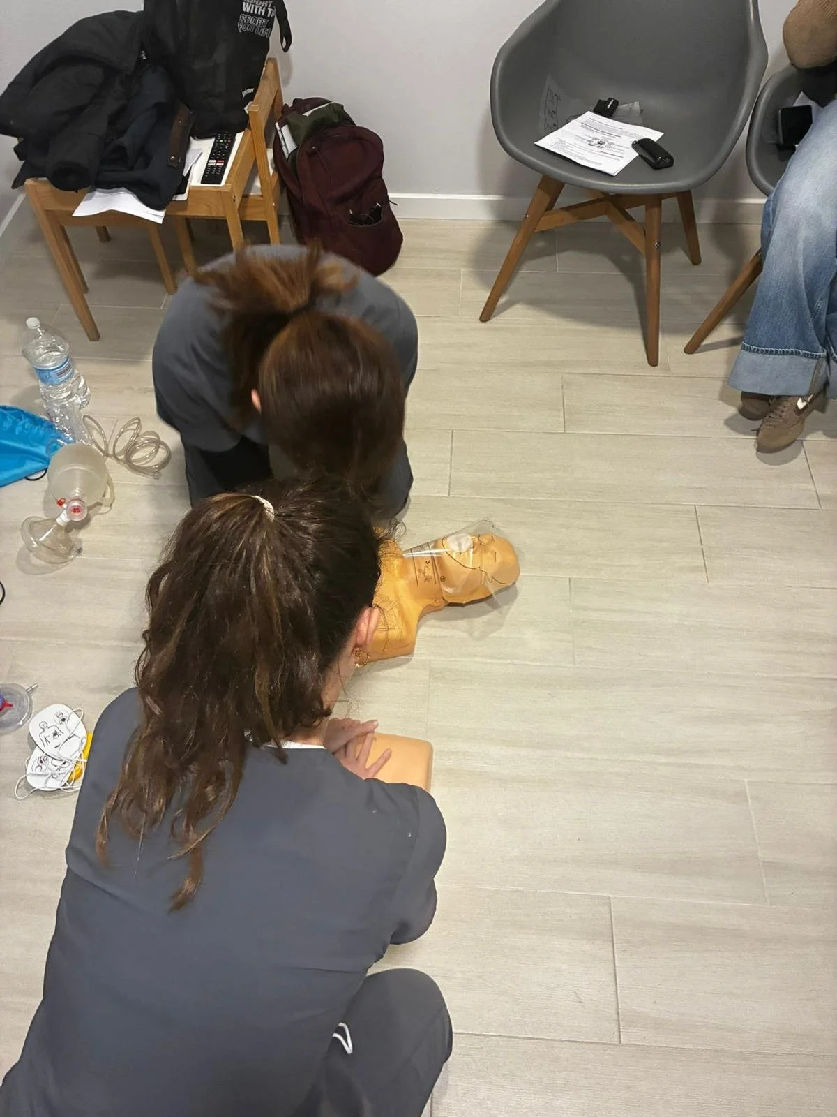 Dos personas capacitándose en técnicas de resucitación en una máquina de entrenamiento para reanimación cardiopulmonar.