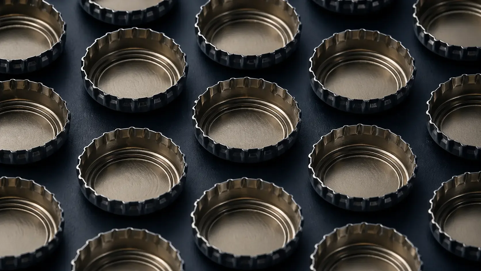 Empty metal bottle caps arranged in a pattern on a dark background.