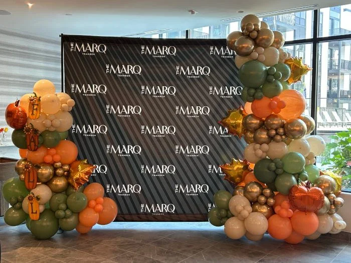 Two balloon trees decorated with various colored balloons, stars, and the letter balloons spelling 'FINAL'. A black backdrop with white text reads 'THE MARQ' and 'TEAMER'.