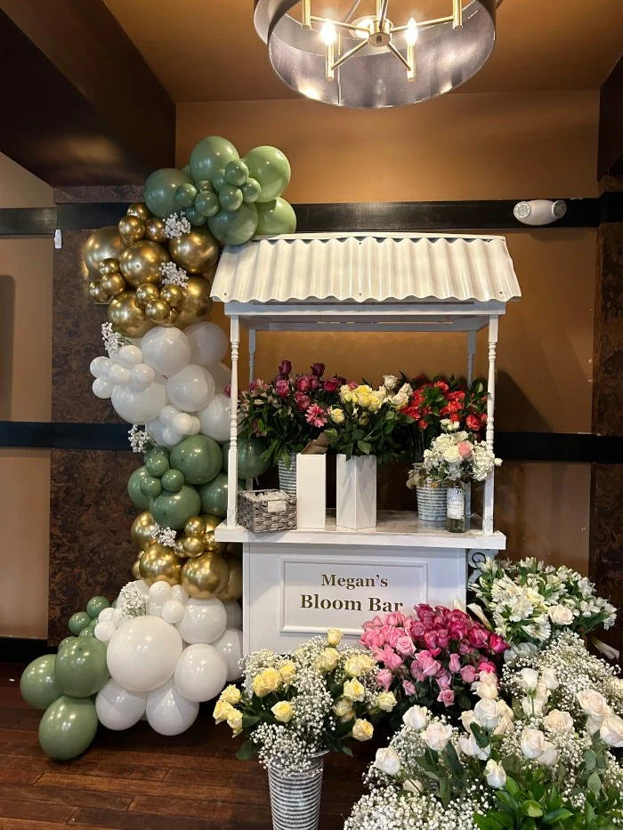 A floral display stand named 'Megan's Bloom Bar' decorated with various flowers.