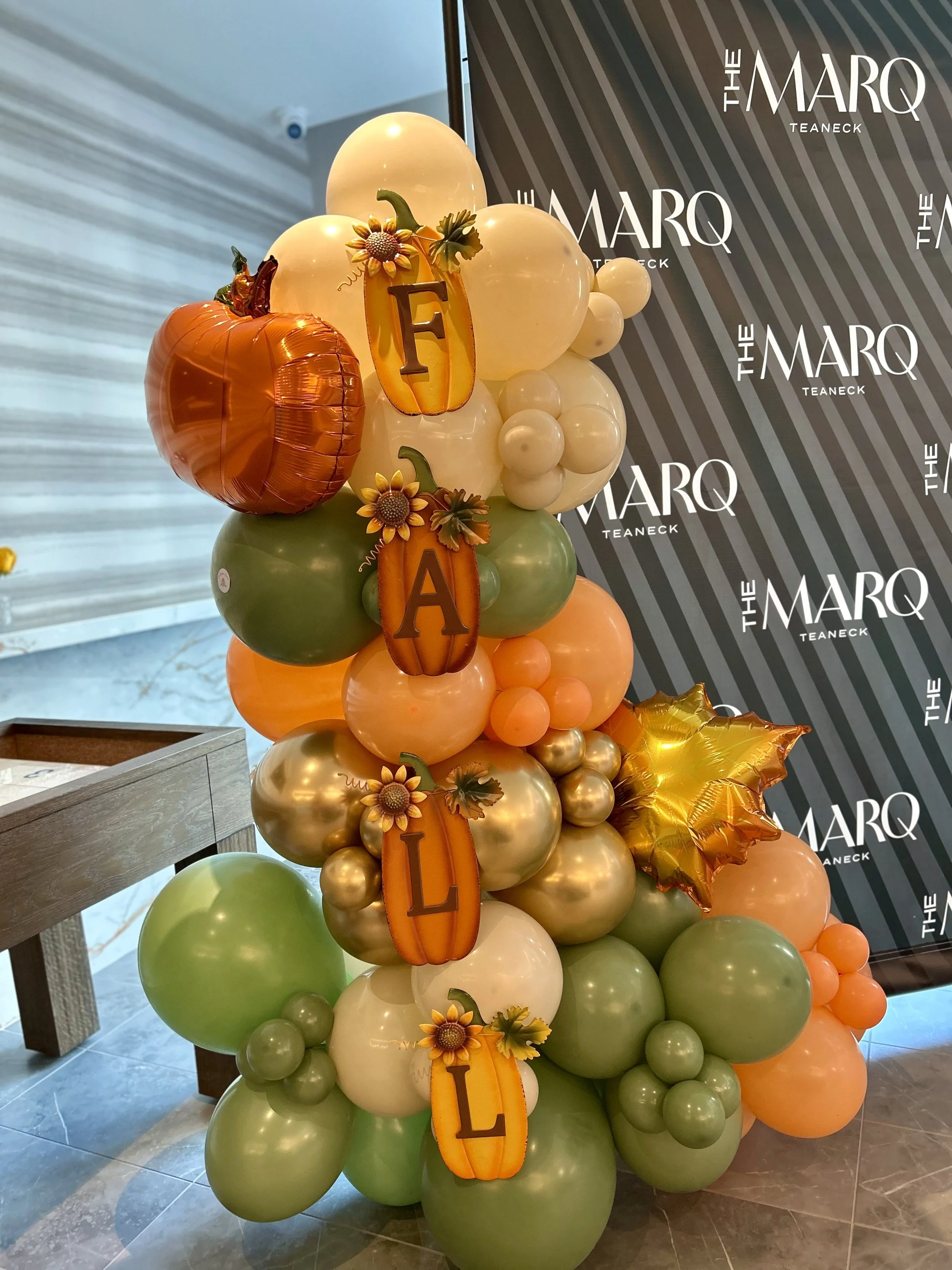 Decorative balloon arrangement with pumpkins, sunflowers, and fall-themed ornaments.