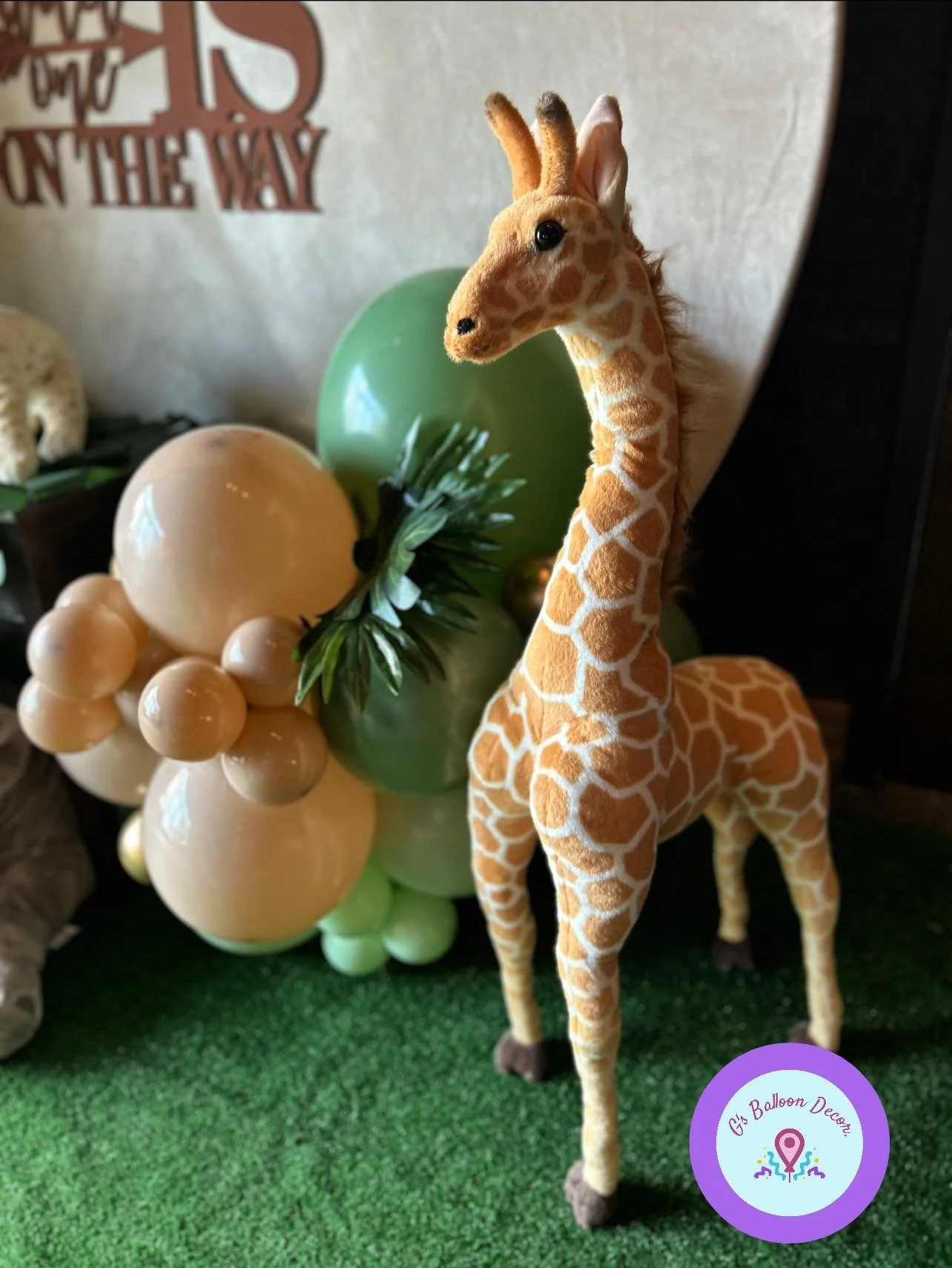 A plush giraffe toy features prominently in front of a balloon display.
