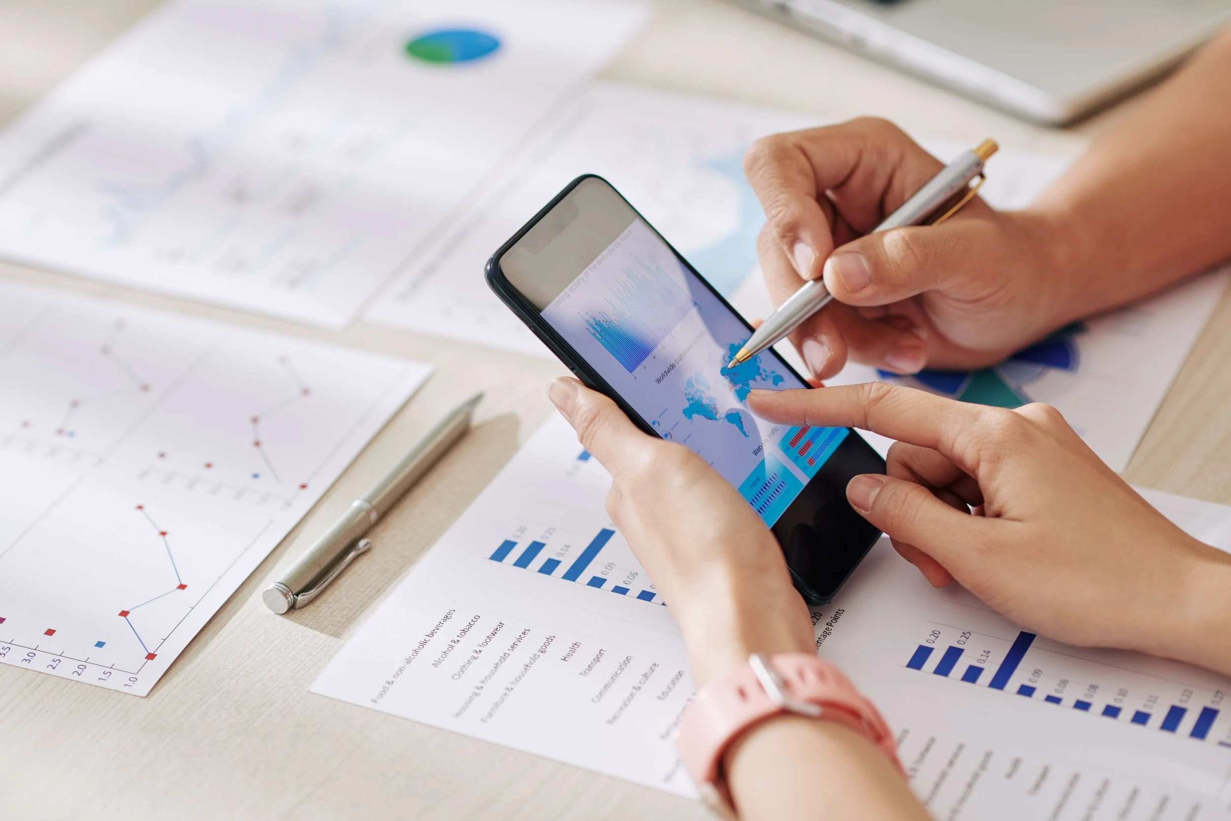 a man and a woman hand holding a smart phone and pointing at a graphic on the phone
