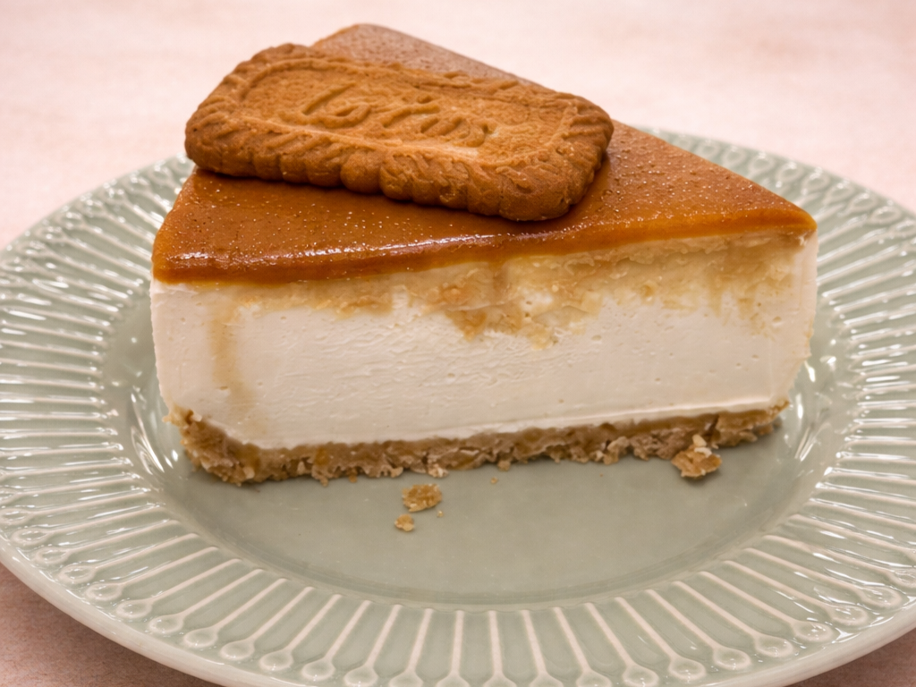 A slice of cheesecake topped with a cookie on a clear, decorative plate