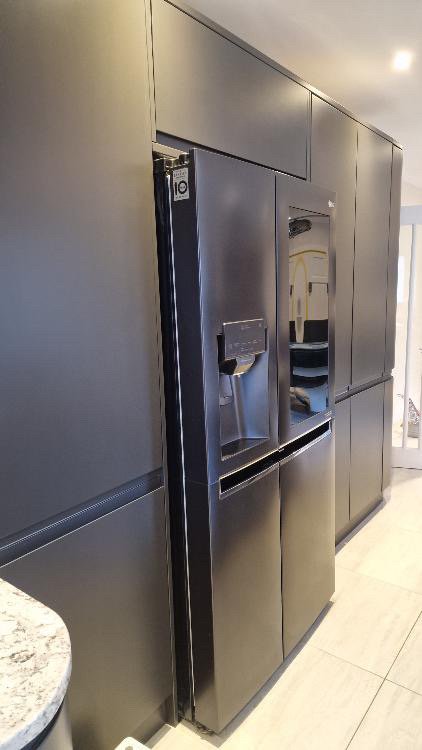 Black side-by-side refrigerator with water and ice dispenser in a modern kitchen.