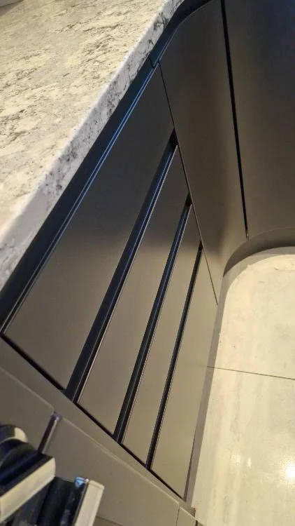 Close-up of black kitchen cabinets and part of a granite countertop.
