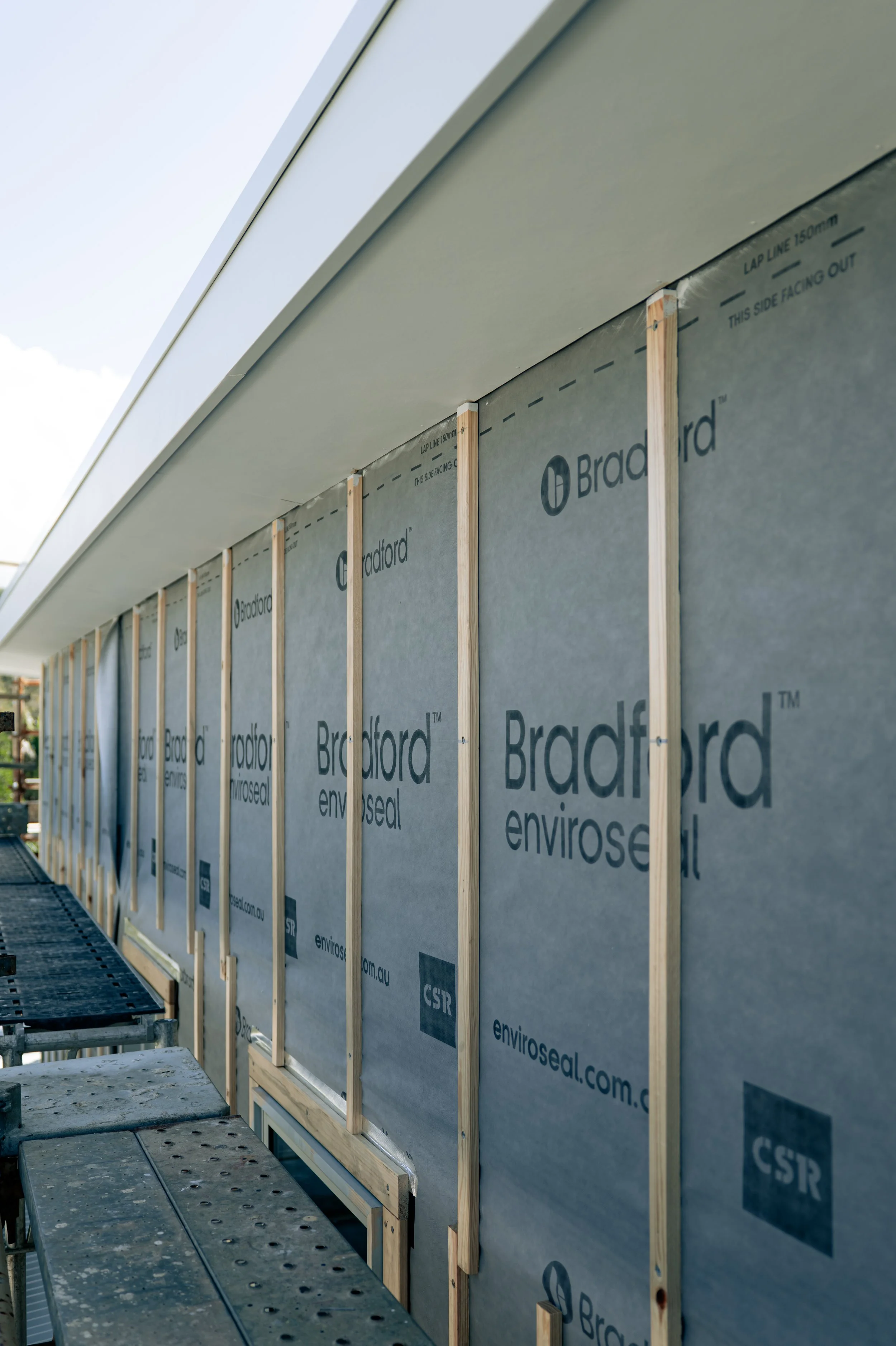 Construction site with Wood framing and Bradfords Enviroseal weather-resistant barrier on the exterior wall of a building under construction.