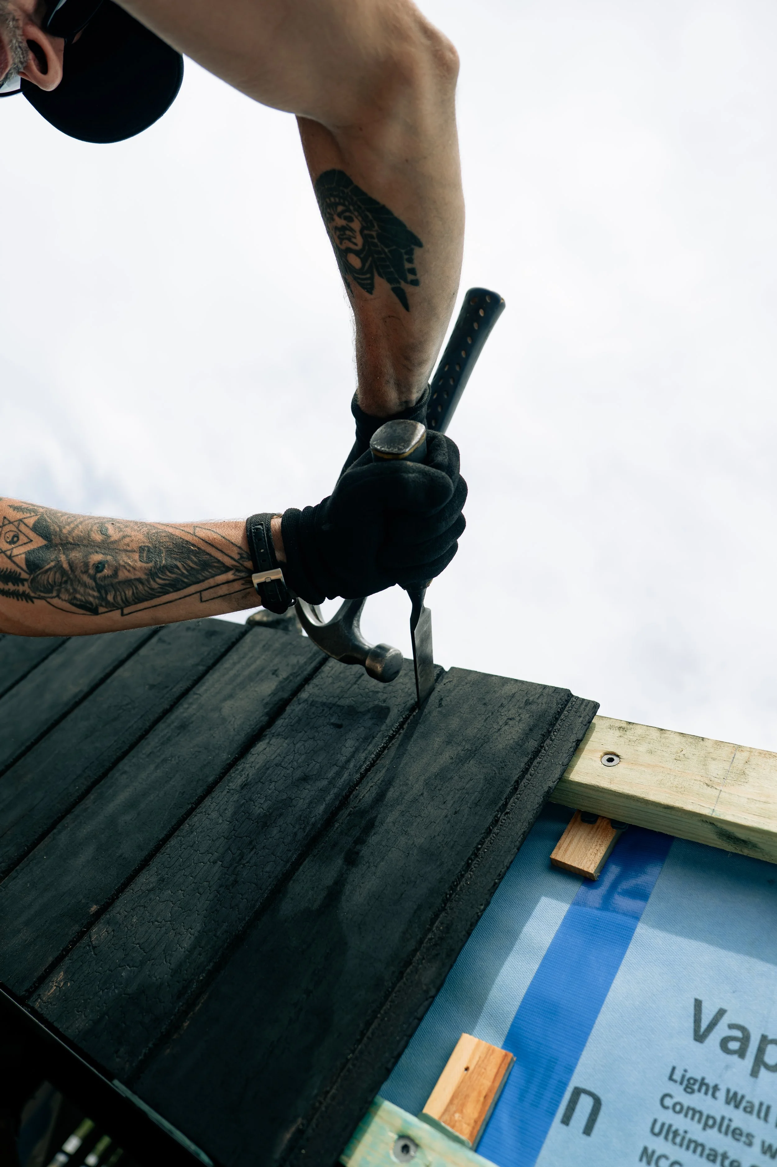 A person using a hammer and chisel to work on a wooden surface outdoors.