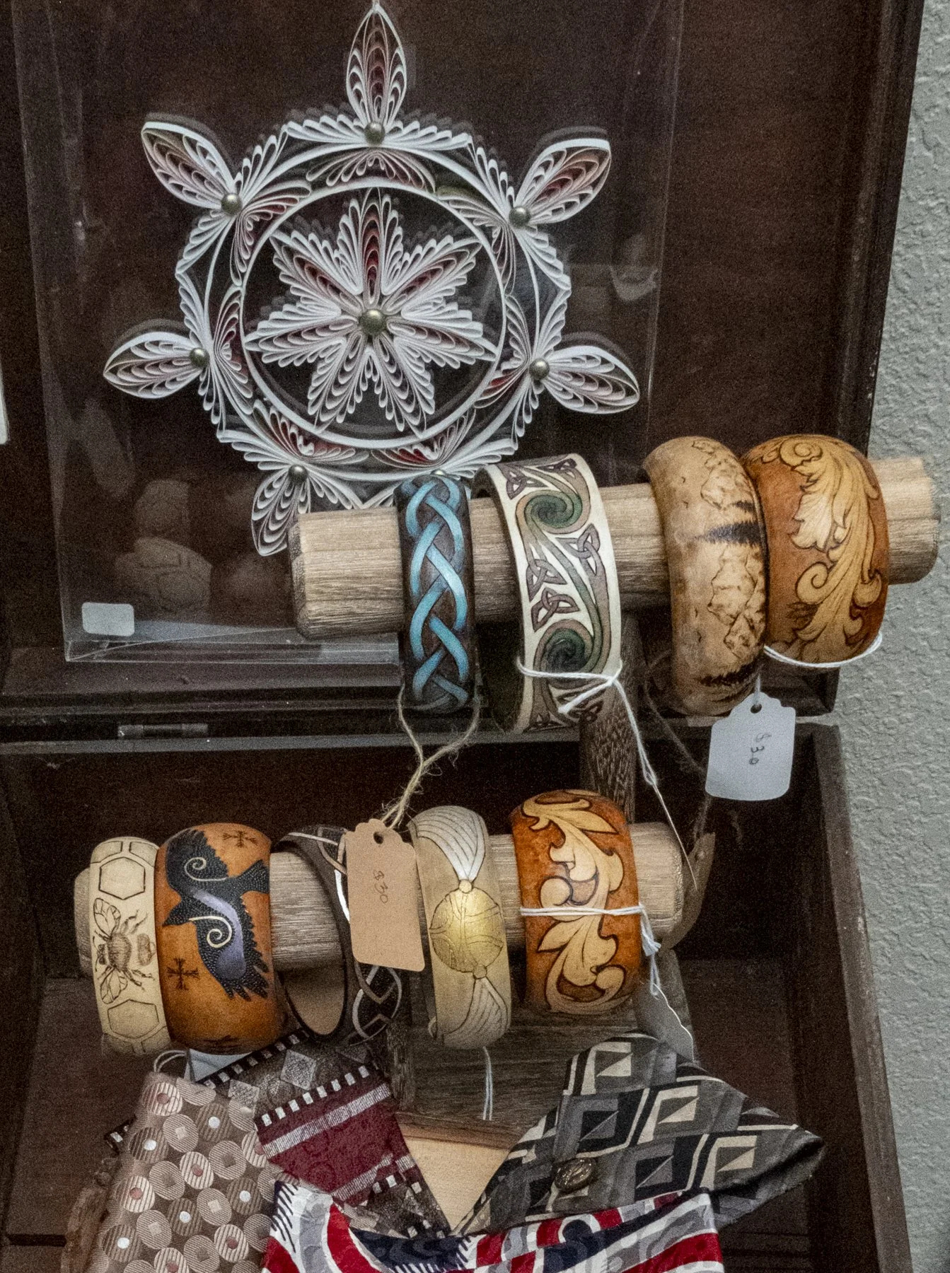 Display of handcrafted bracelets and decorative items on wooden rods and cloth tags, with intricate designs and patterns.