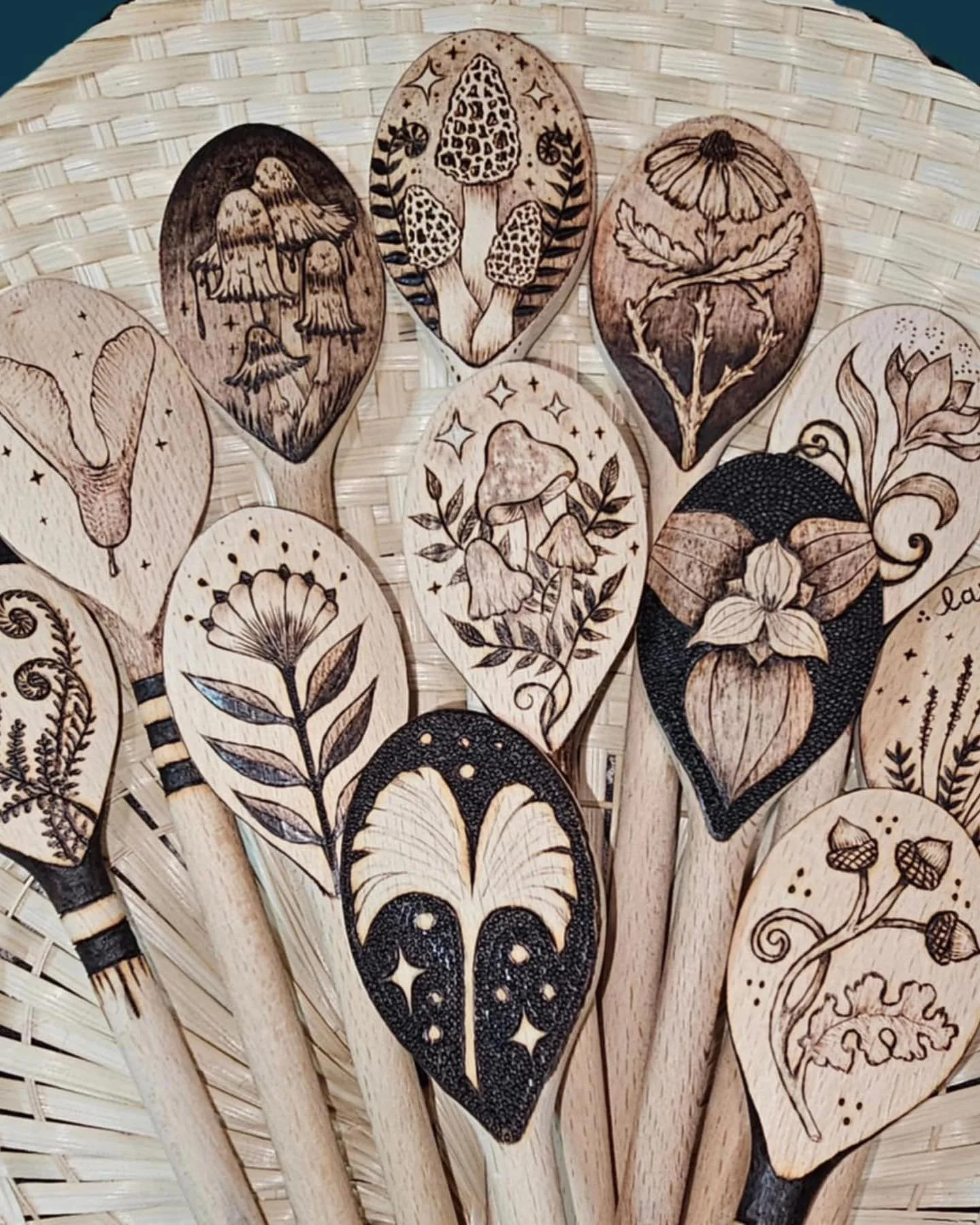 Close-up of wooden paddle fans with engraved nature-inspired designs, including mushrooms, flowers, and leaves, arranged in a fan shape.