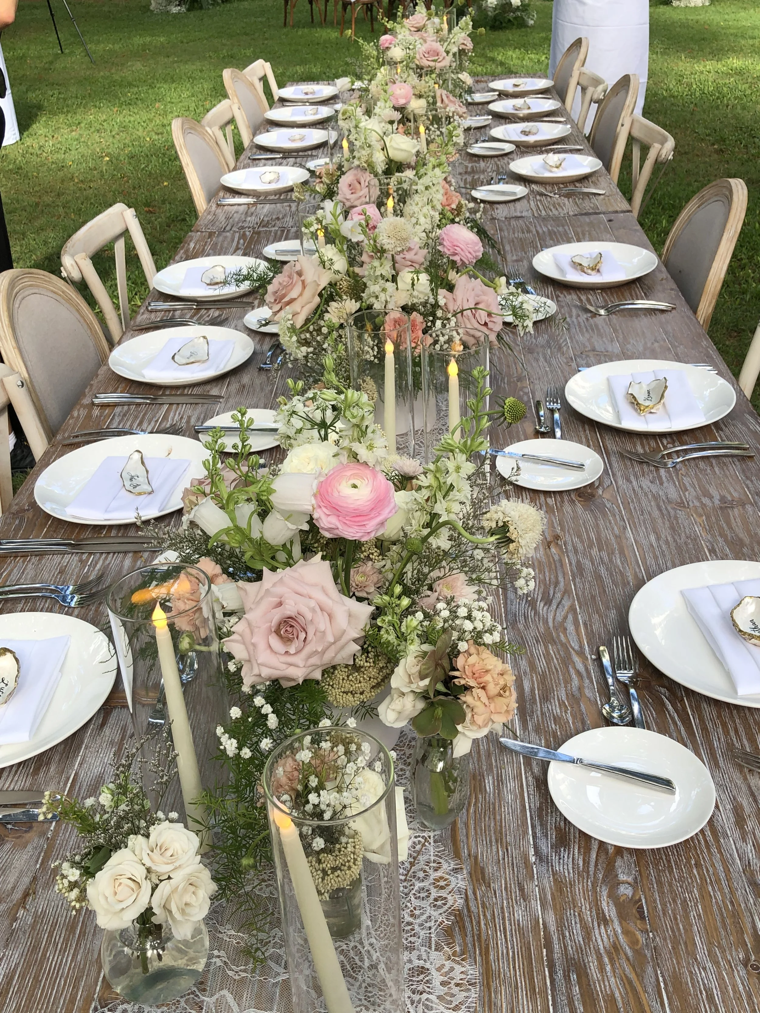 outdoors on a lawn a long table set with florals down the center
