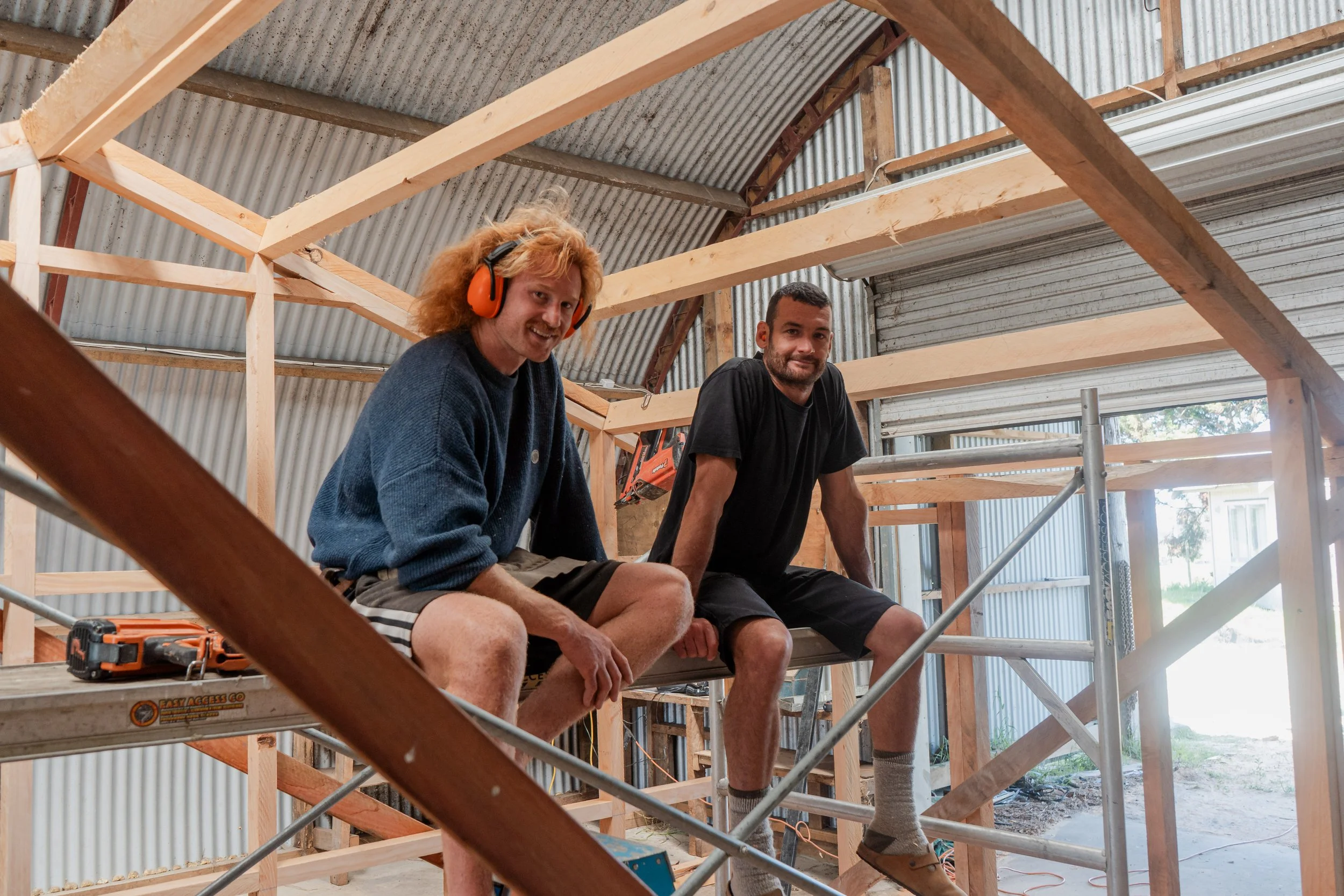 Tom and Louis, Co-Founders of Yutori Sauna, sitting on a wooden scaffold inside a Yutori Sauna under construction.
