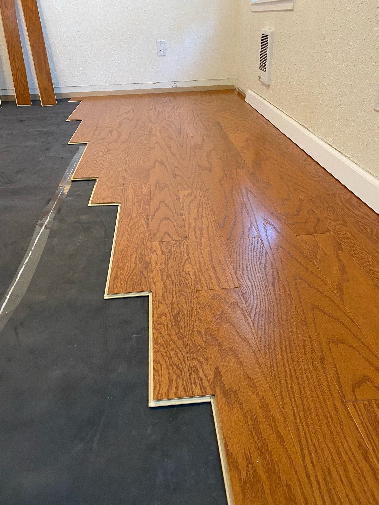 The photo shows a partially installed engineered hardwood floor.