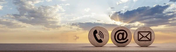 Sunset over ocean with three round stones displaying a phone icon, a website at symbol, and an envelope icon